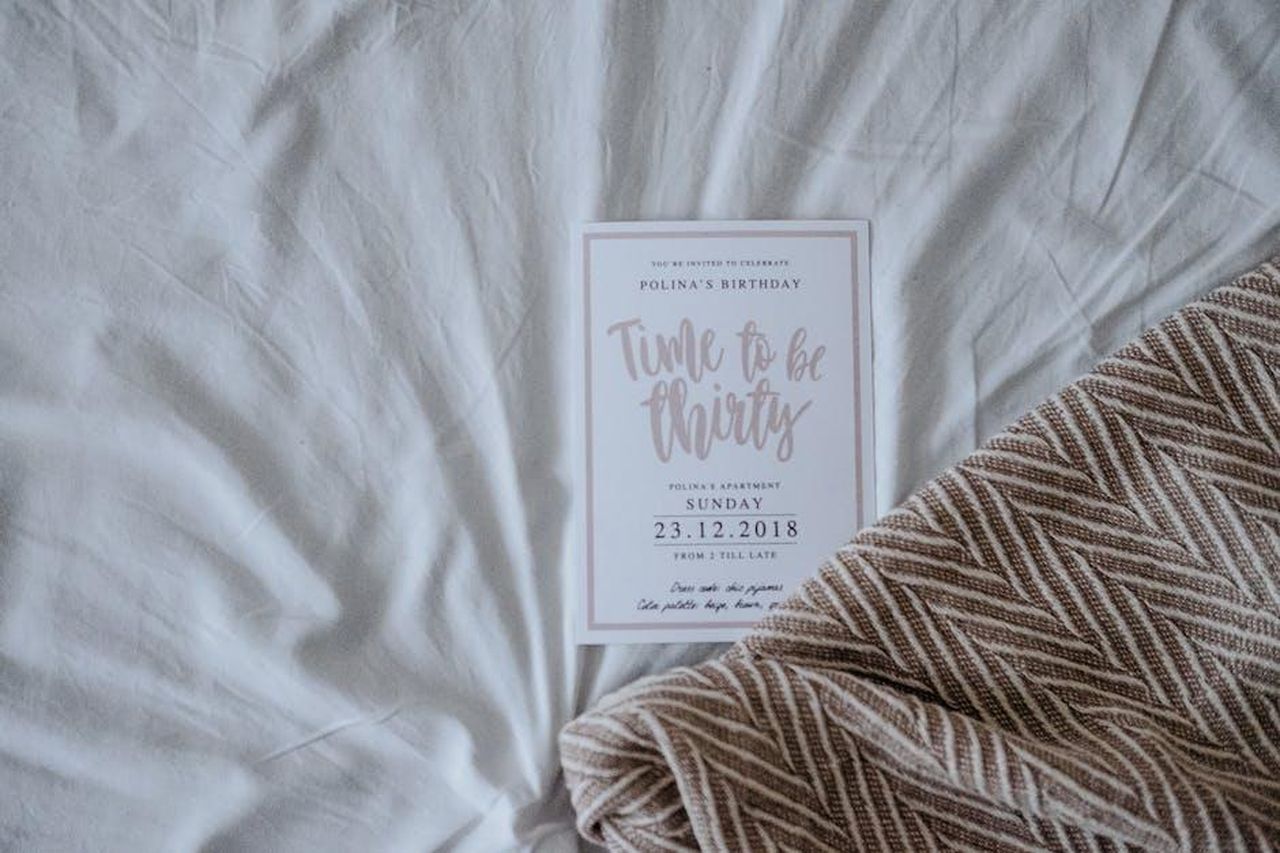 Informazioni_pratiche_sulla_festa_AnjQqe6uwx - Veicoli24 Source: Lena Shekhovtsova - pexels - A chic invitation card for a 30th birthday celebration resting on a soft fabric background.
