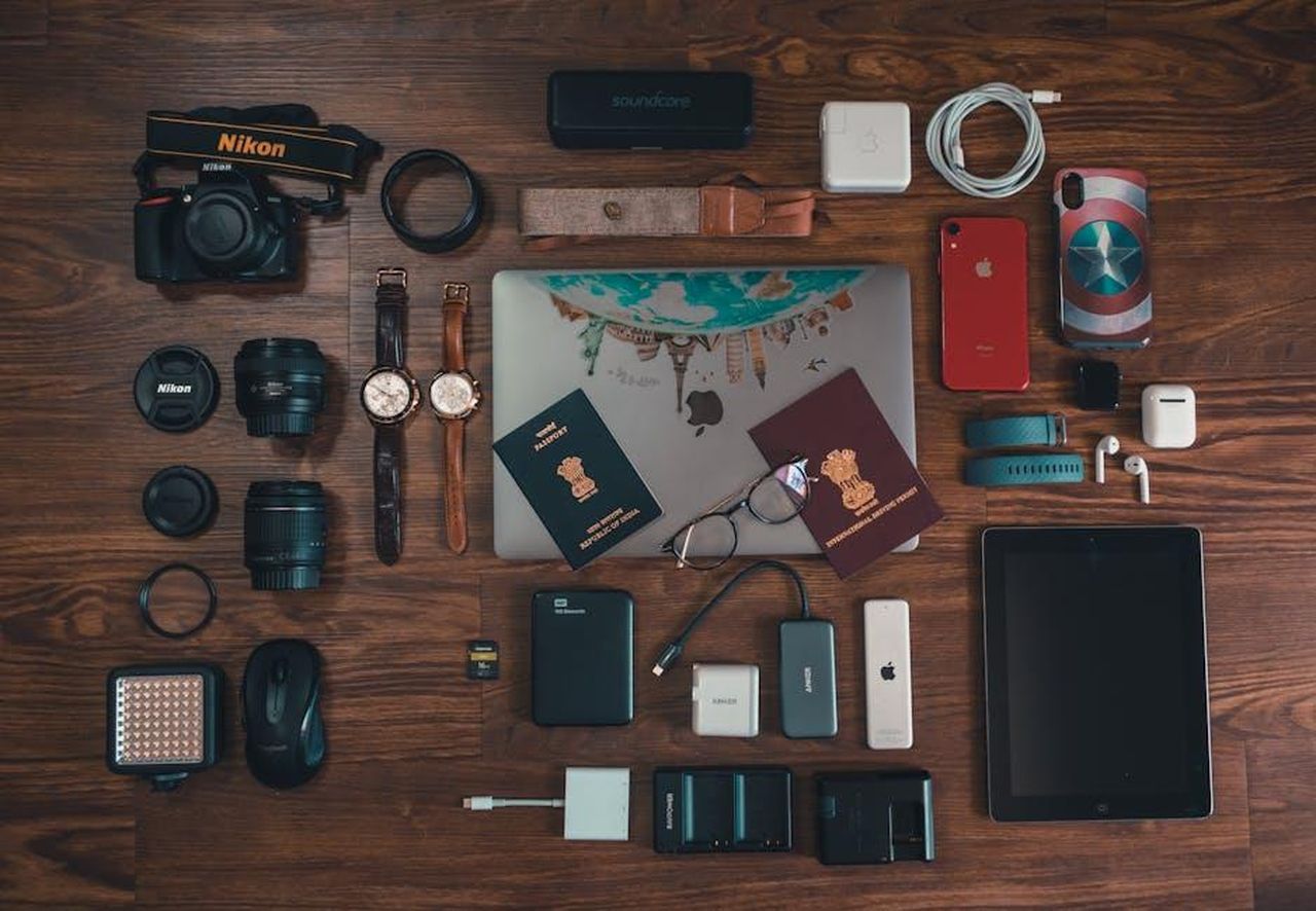 Innovazioni_nella_tecnologia_delle_batterie_jIThPWGiTG - Veicoli24 Source: Hiren Lad - pexels - Flat lay of travel essentials including gadgets, passports, and camera on wooden surface.
