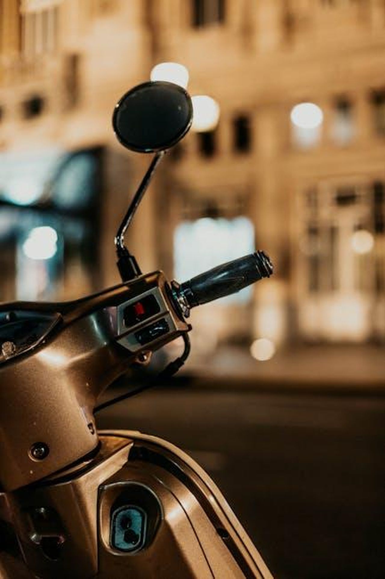 Innovazioni_tecnologiche_nel_settore_automobilistico_2MEVrXhuYu - Veicoli24 Source: Gera Cejas - pexels - Stylish scooter handle against blurred city lights at night, capturing urban elegance.