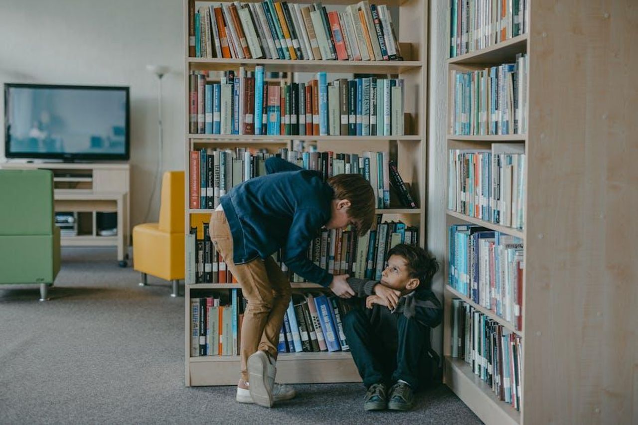 Intervento_del_Tesoro_e_implicazioni_per_i_consumatori_Mo2YSPSOAU - Veicoli24 Source: Mikhail Nilov - pexels - A child bullies another student in a school library, highlighting social issues.