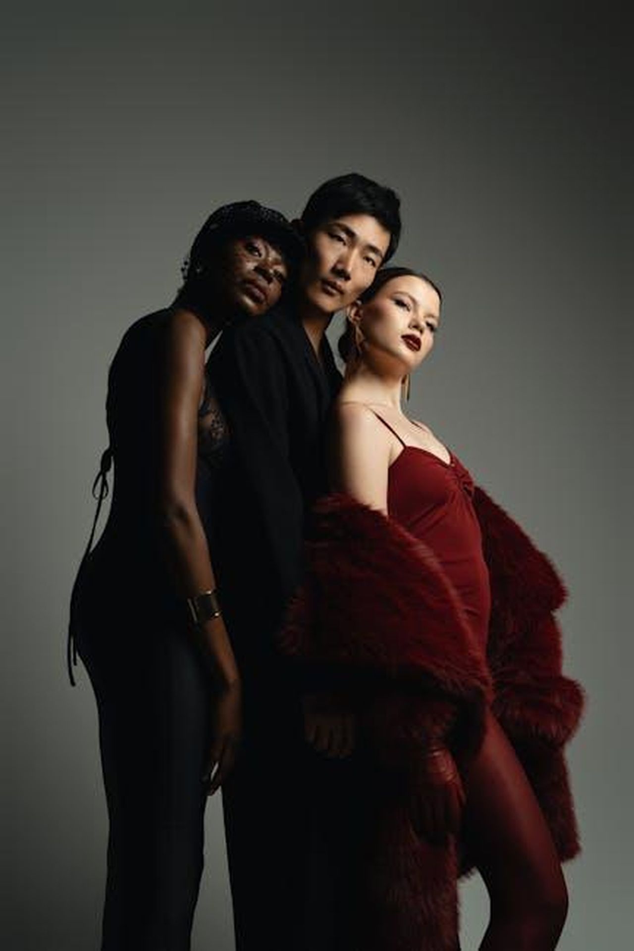 La_partnership_tra_Toyota_e_Christian_Siriano_nAT3L3zgP0 - Veicoli24 Source: Jay Soundo - pexels - Three models pose elegantly in a studio, showcasing diverse fashion styles and moody lighting.