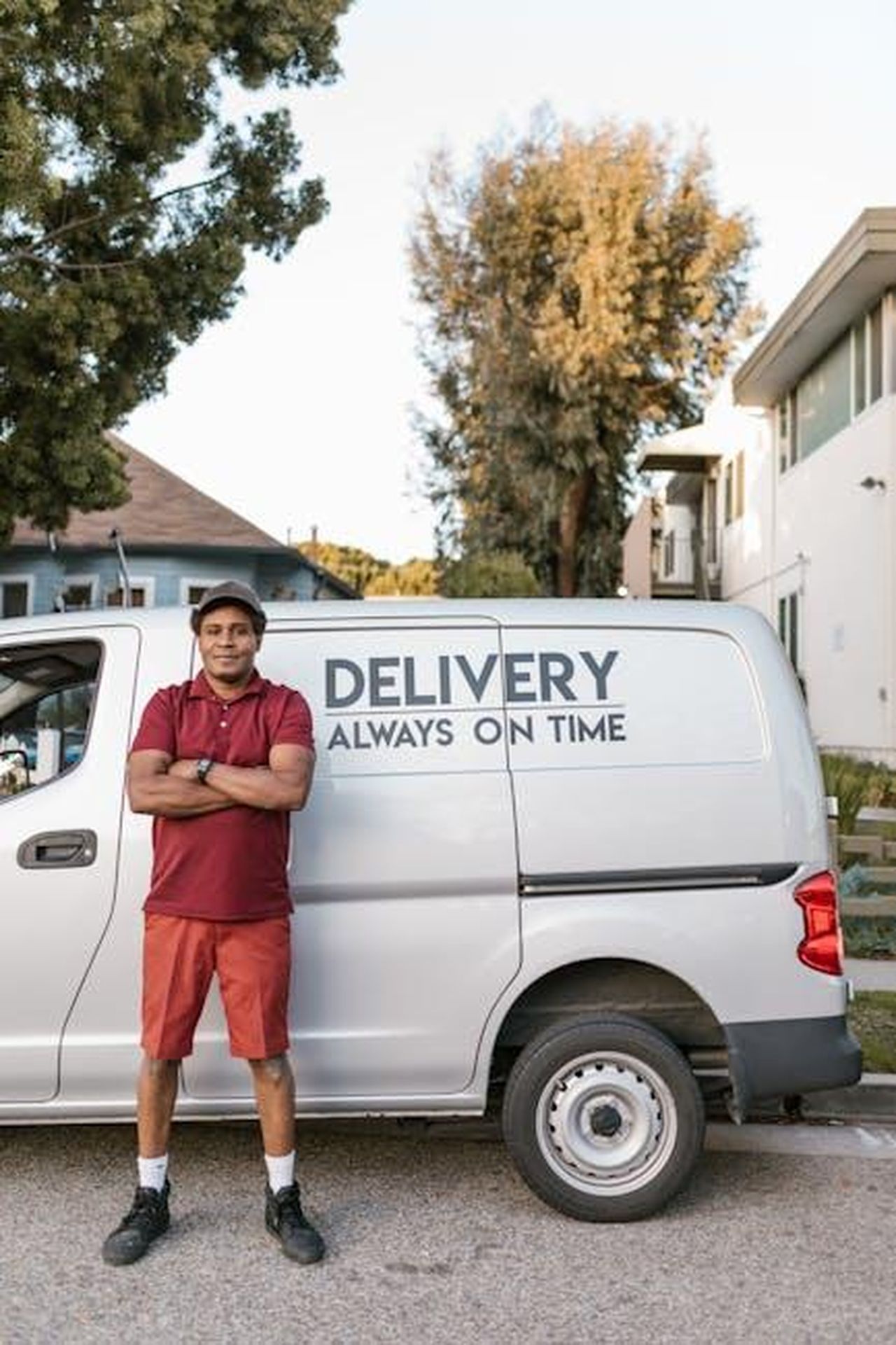 Le_auto_pi_affidabili_e_il_loro_costo_hLDQ9KNxU3 - Veicoli24 Source: RDNE Stock project - pexels - Confident delivery driver in uniform standing beside a punctual delivery service van outdoors.