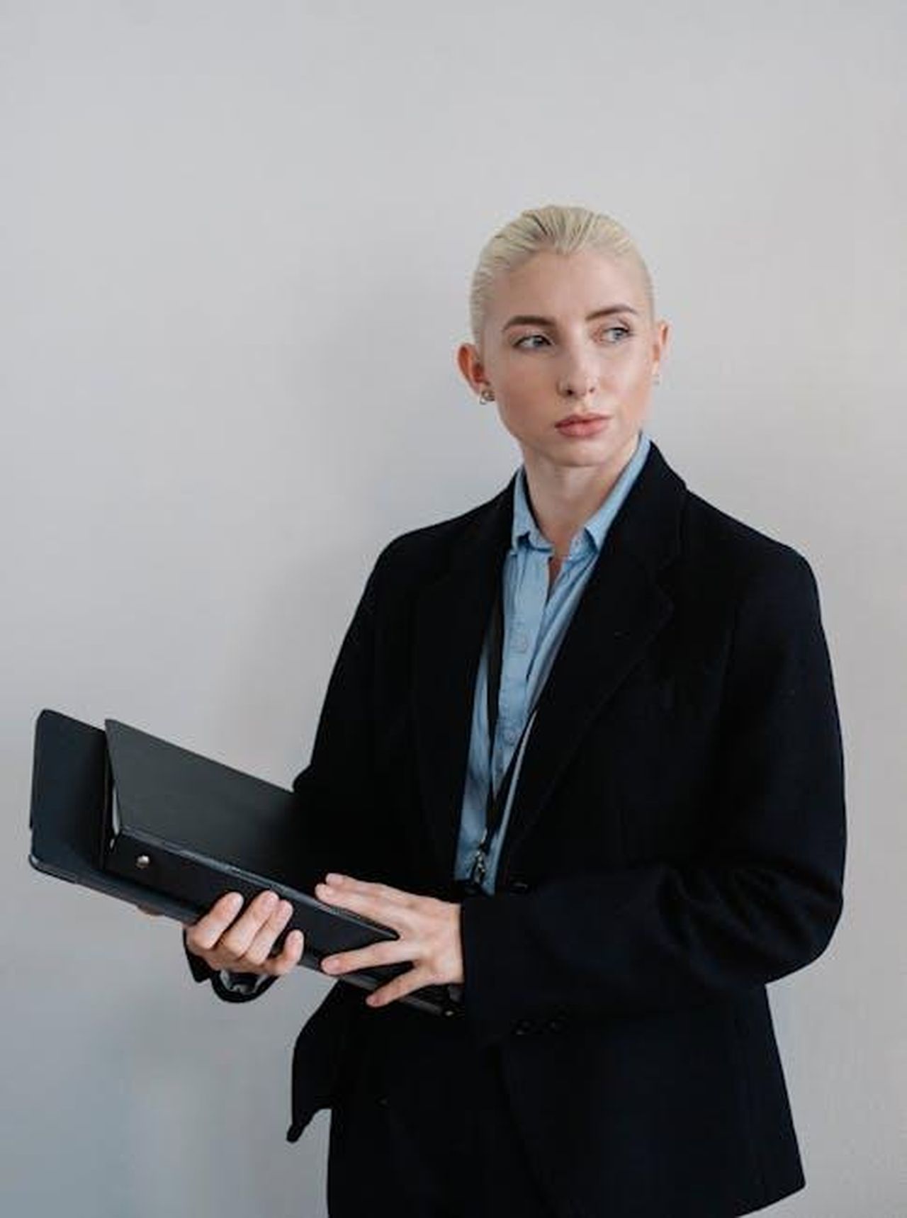 Le_dichiarazioni_di_Axel_Dewitz_3rsBjlDse9 - Veicoli24 Source: Sora Shimazaki - pexels - Confident businesswoman in a corporate setting holding a folder, looking thoughtfully to the side.