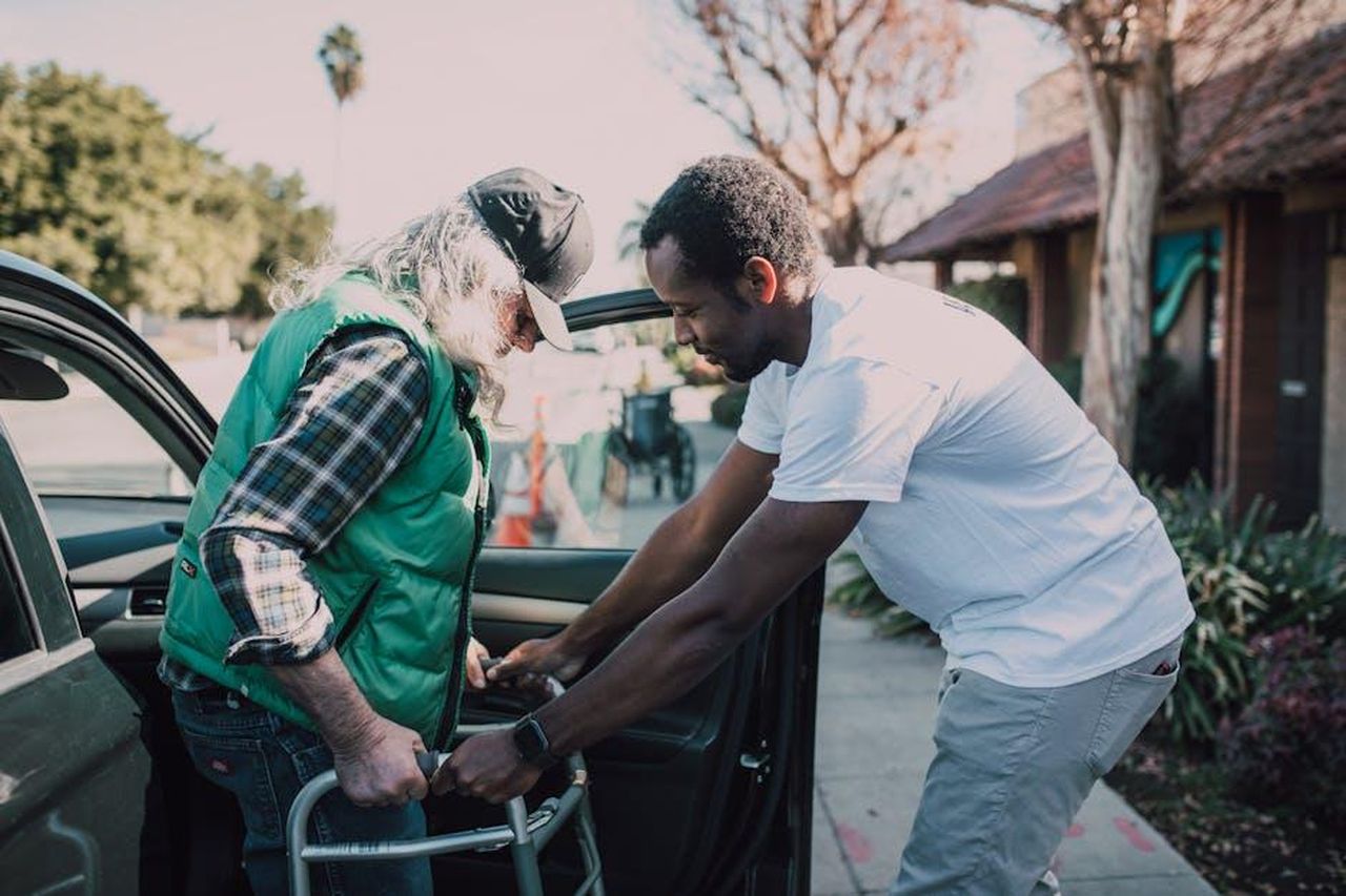 Le_misure_adottate_da_Mitsubishi_kCHdqPLQDj - Veicoli24 Source: RDNE Stock project - pexels - Young volunteer helping senior man with walker near a parked car, symbolizing care and support.