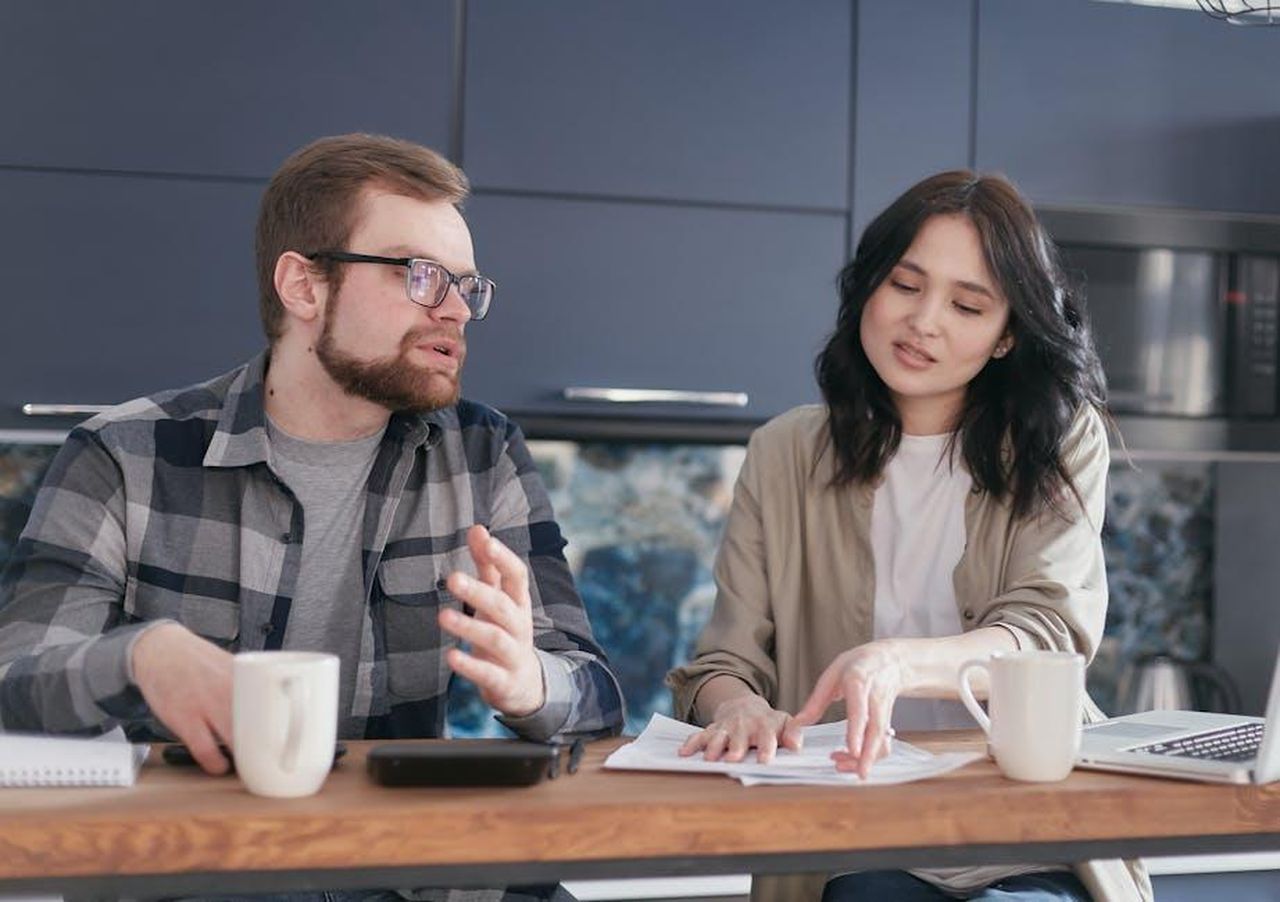 Le_sfide_finanziarie_di_Nikola_dsCS18zLz7 - Veicoli24 Source: Mikhail Nilov - pexels - A young couple discusses financial documents at a cozy home setting, expressing concern.