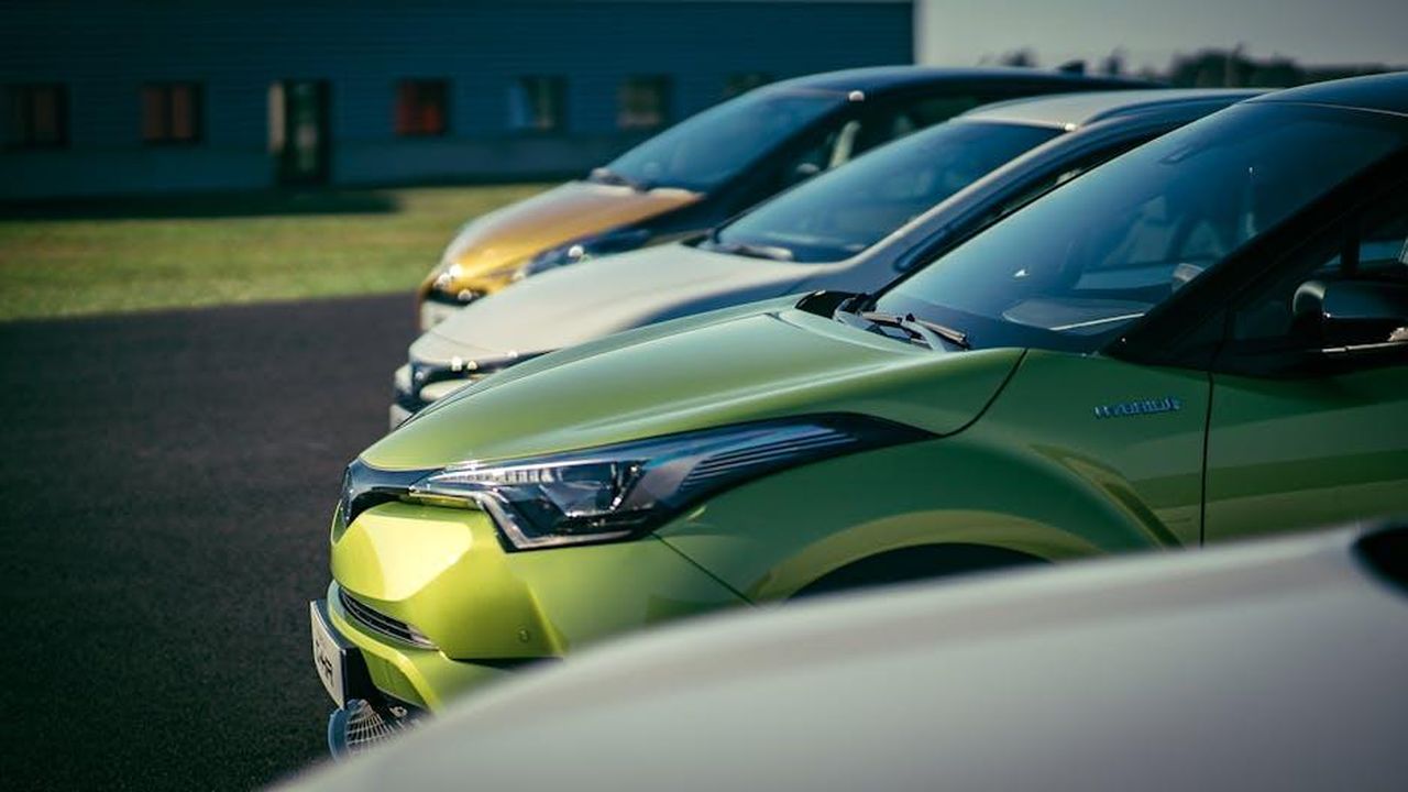 Le_versioni_Harvester_non_tireranno_come_gli_EV_fL8N2pyUvm - Veicoli24 Source: Grégory Costa - pexels - A row of brightly colored cars parked outdoors under daylight, showcasing their vibrant paint and shiny exteriors.