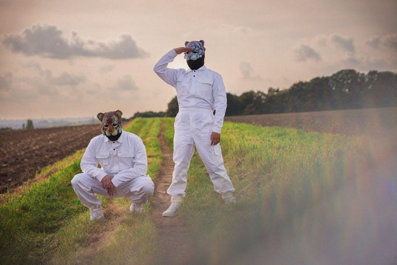 Le_versioni_ibride_di_CRV_e_Accord_i_pi_popolari_7NJpxcREMX - Veicoli24 Source: Flo Zimmermann - pexels - Two masked individuals in white outfits stand and squat in a rural field.