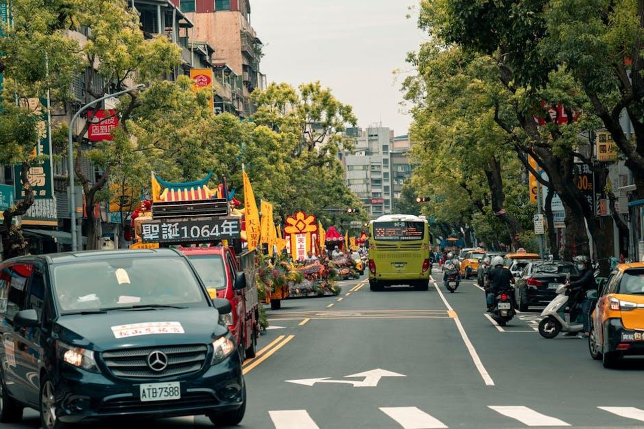 Mercedes_offre_ora_furgoni_a_benzina_accanto_a_quelli_elettrici_Pnc90rjN1f - Veicoli24 Source: Jimmy Liao - pexels - Colorful vehicles and decorations on a lively city street during a festive parade.