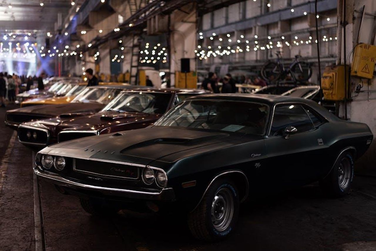 Minacce_e_sfide_future_vCXOQLrmAH - Veicoli24 Source: Vitali Adutskevich - pexels - Lineup of classic cars in an industrial indoor setting with ambient lighting.