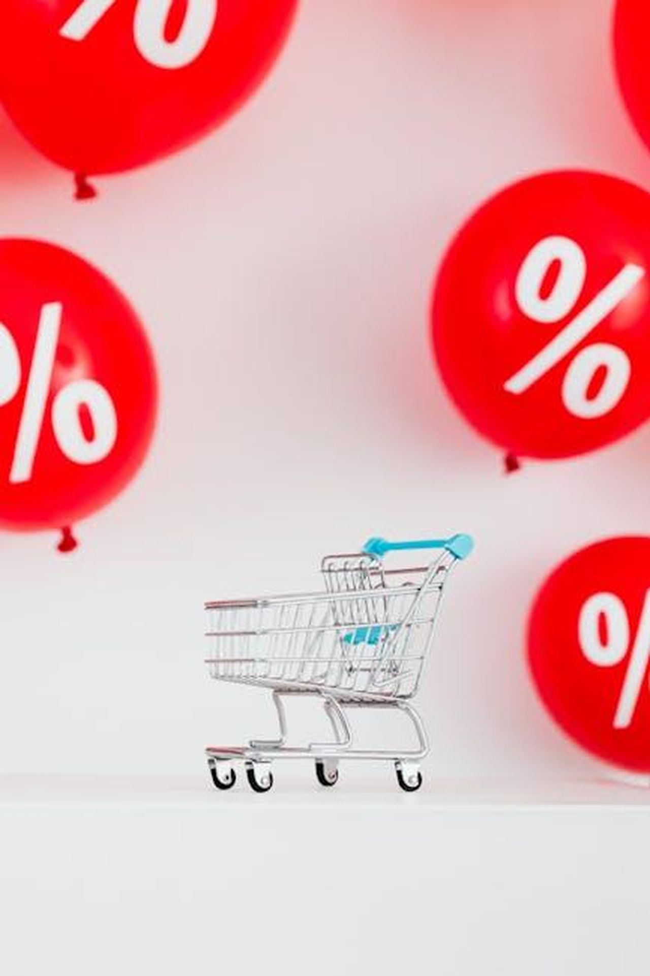 Misure_richieste_dagli_automobilisti_per_affrontare_i_costi_HfrSoz0zVU - Veicoli24 Source: Photo By: Kaboompics.com - pexels - Mini shopping cart with red percentage balloons on a white background, symbolizing sales.