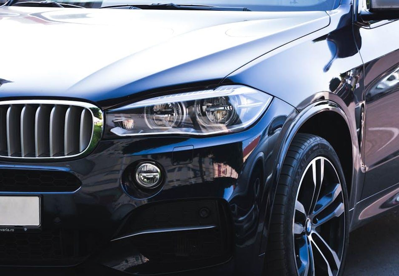 Modalit_Infinity_sblocca_la_potenza_completa_MjcboCI6Iu - Veicoli24 Source: Mihis Alex - pexels - Close-up of a black luxury car showcasing intricate headlight and front grille details.