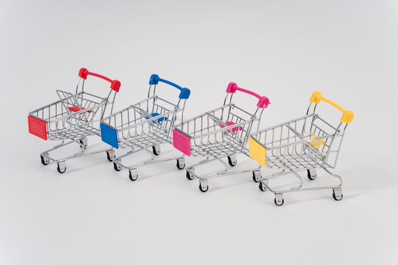 Modelli_Mini_e_vendite_negli_Stati_Uniti_A5GFAIqzan - Veicoli24 Source: Sora Shimazaki - pexels - Four miniature shopping carts with colorful handles aligned on a white background for conceptual business imagery.