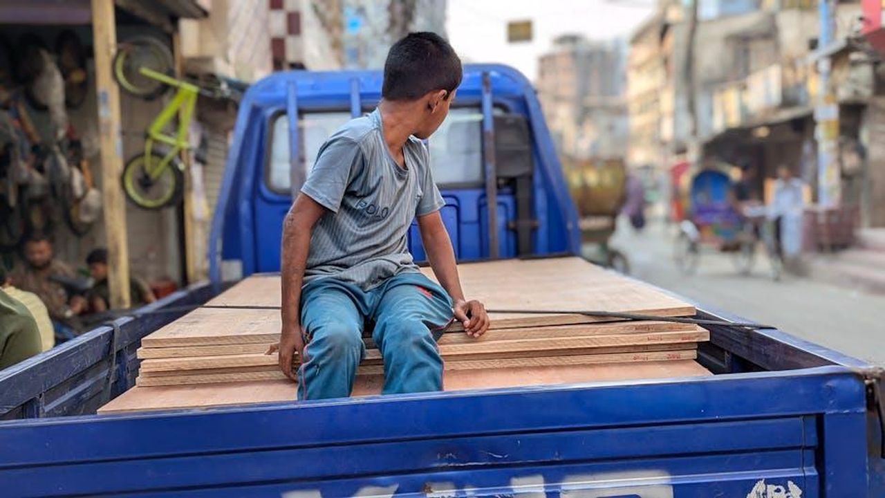 Motivi_dei_ritardi_e_specifiche_tecniche_hIsgLQmMgI - Veicoli24 Source: Salah Uddin - pexels - A teenage boy sits on the back of a truck in a bustling city street, showcasing daily life.