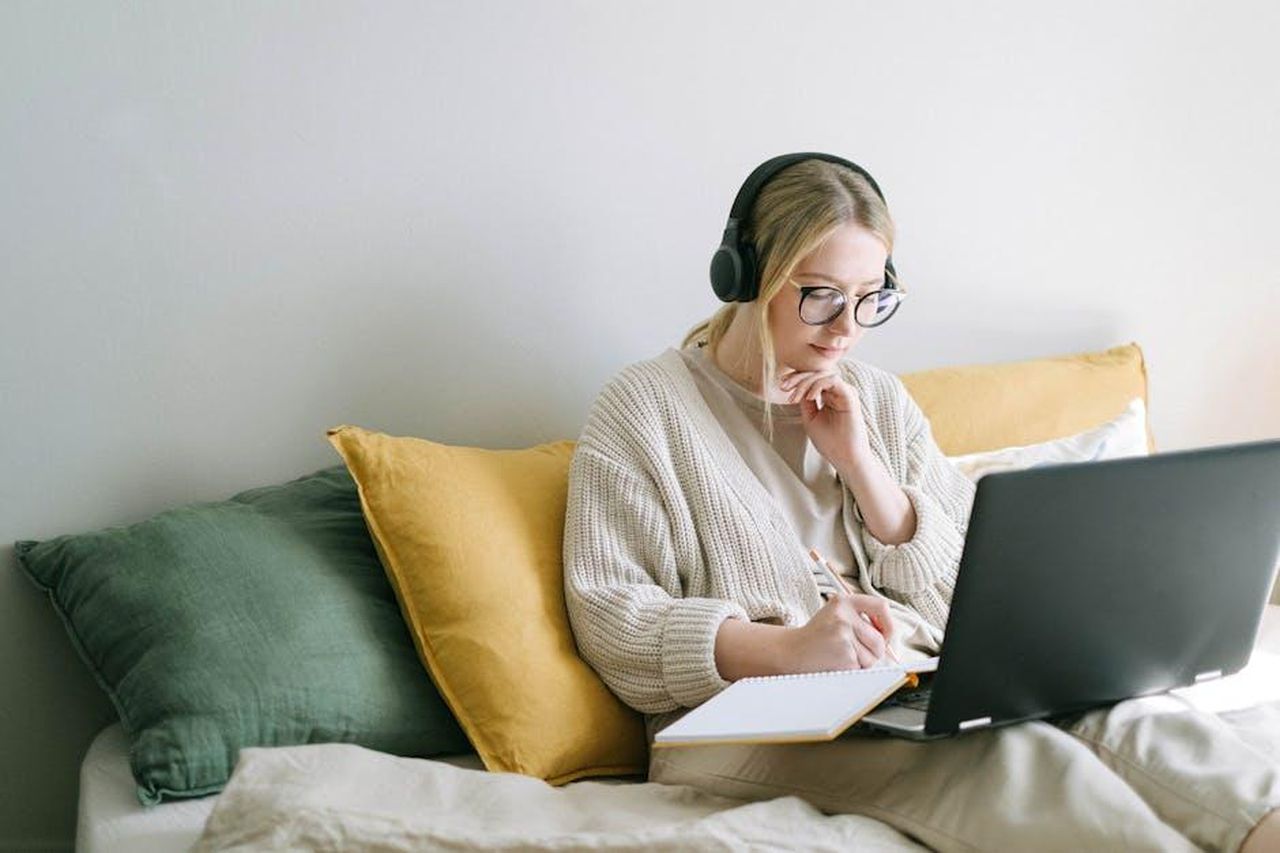 Note_per_i_redattori_SeWGEmLIWF - Veicoli24 Source: Ivan Samkov - pexels - A focused woman in glasses and headphones works on a laptop from a cozy bed.