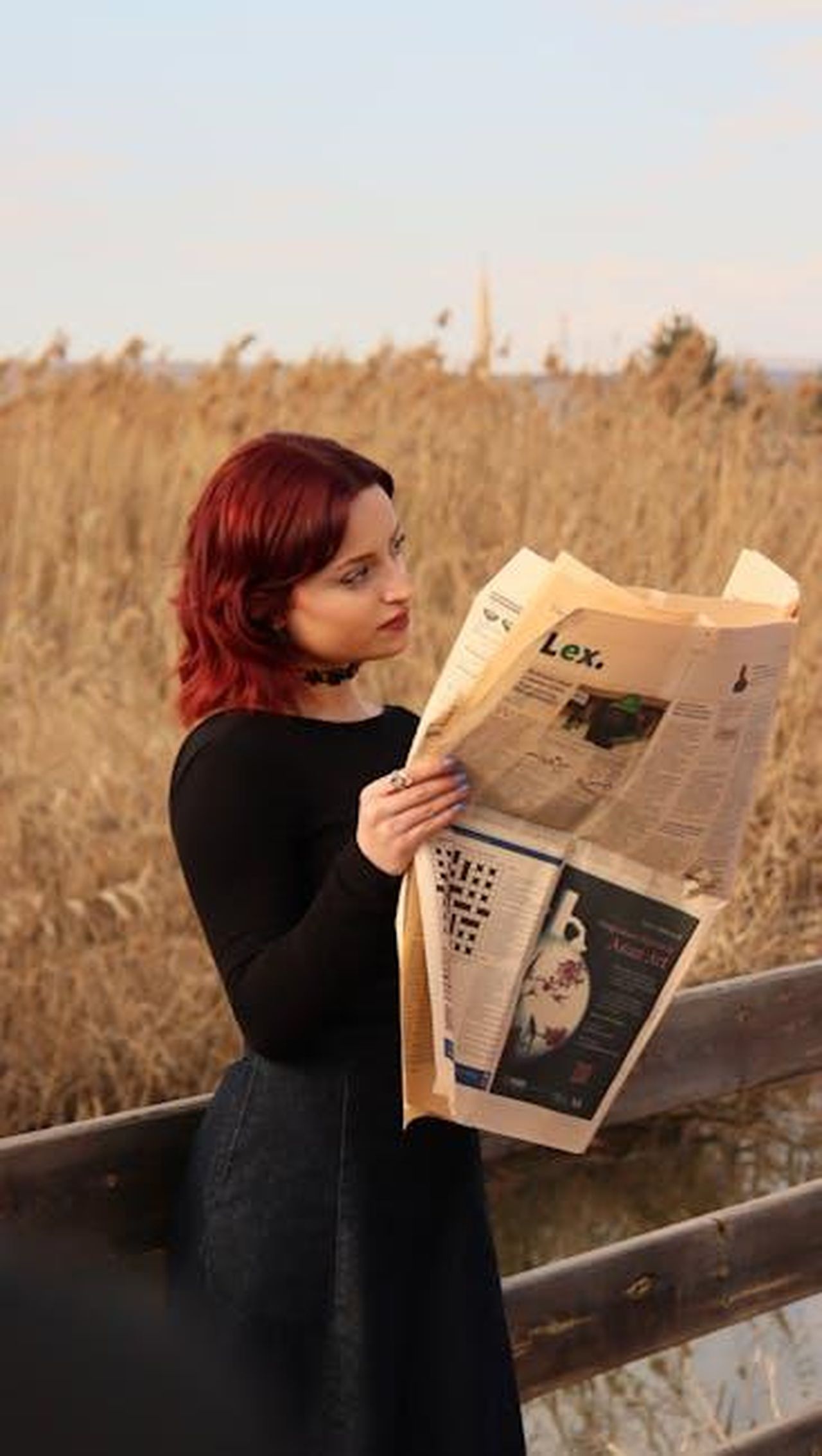Novit_per_la_Ram_1500_del_2025_DDRxFRTzRH - Veicoli24 Source: kübra zehra - pexels - Red-haired woman reads a newspaper in a serene outdoor setting with dry reeds.