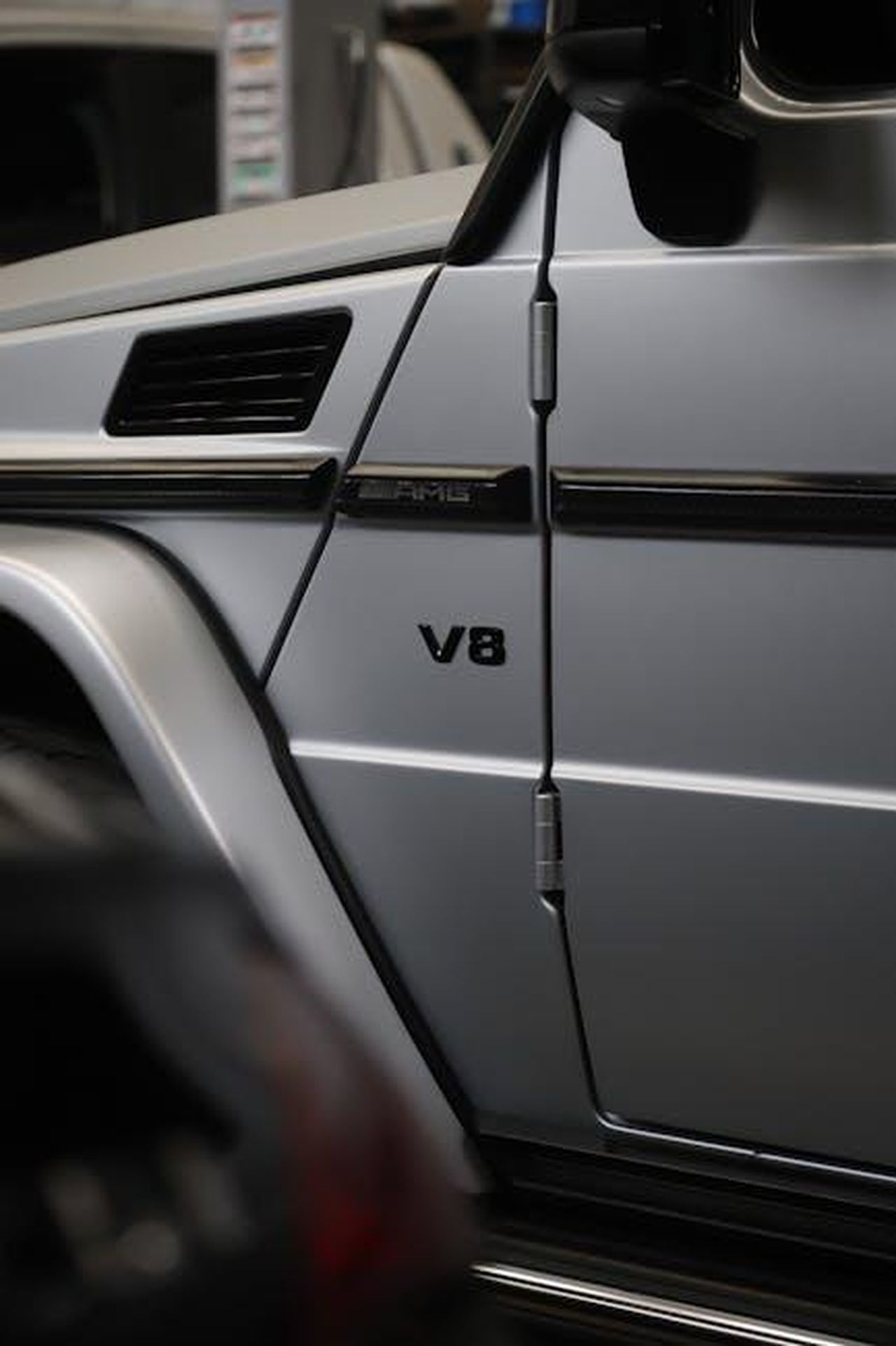 Nuova_generazione_di_motori_V8_elettrificati_22WGKXoBRp - Veicoli24 Source: Sofía Nuñez - pexels - Detailed view of a Mercedes G-Class V8 side panel showcasing sleek design.