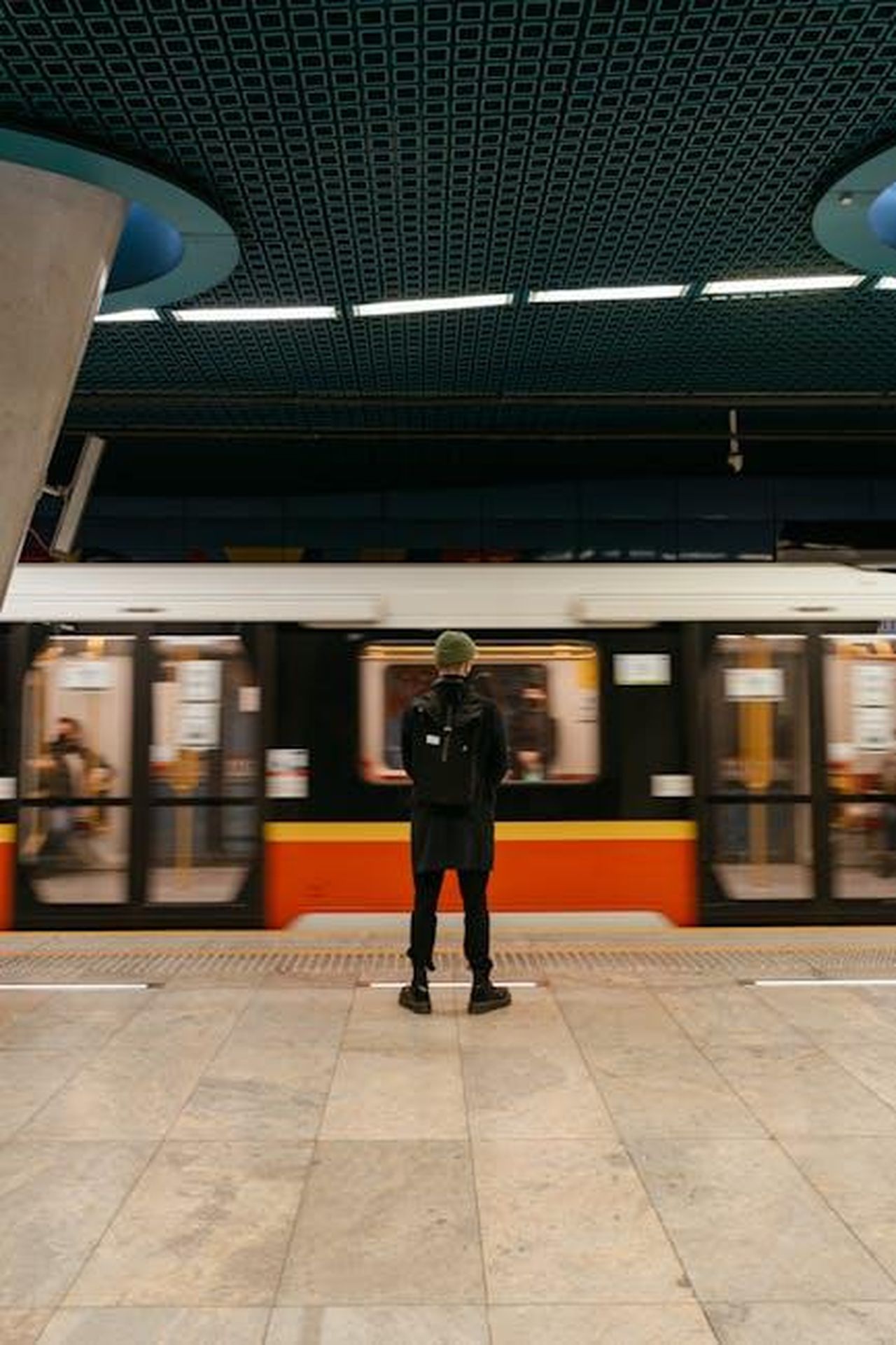 Partnership_in_corso_con_il_produttore_di_ebus_2XVprF28uV - Veicoli24 Source: MART PRODUCTION - pexels - A person stands on a subway platform as a train speeds by in an urban setting.