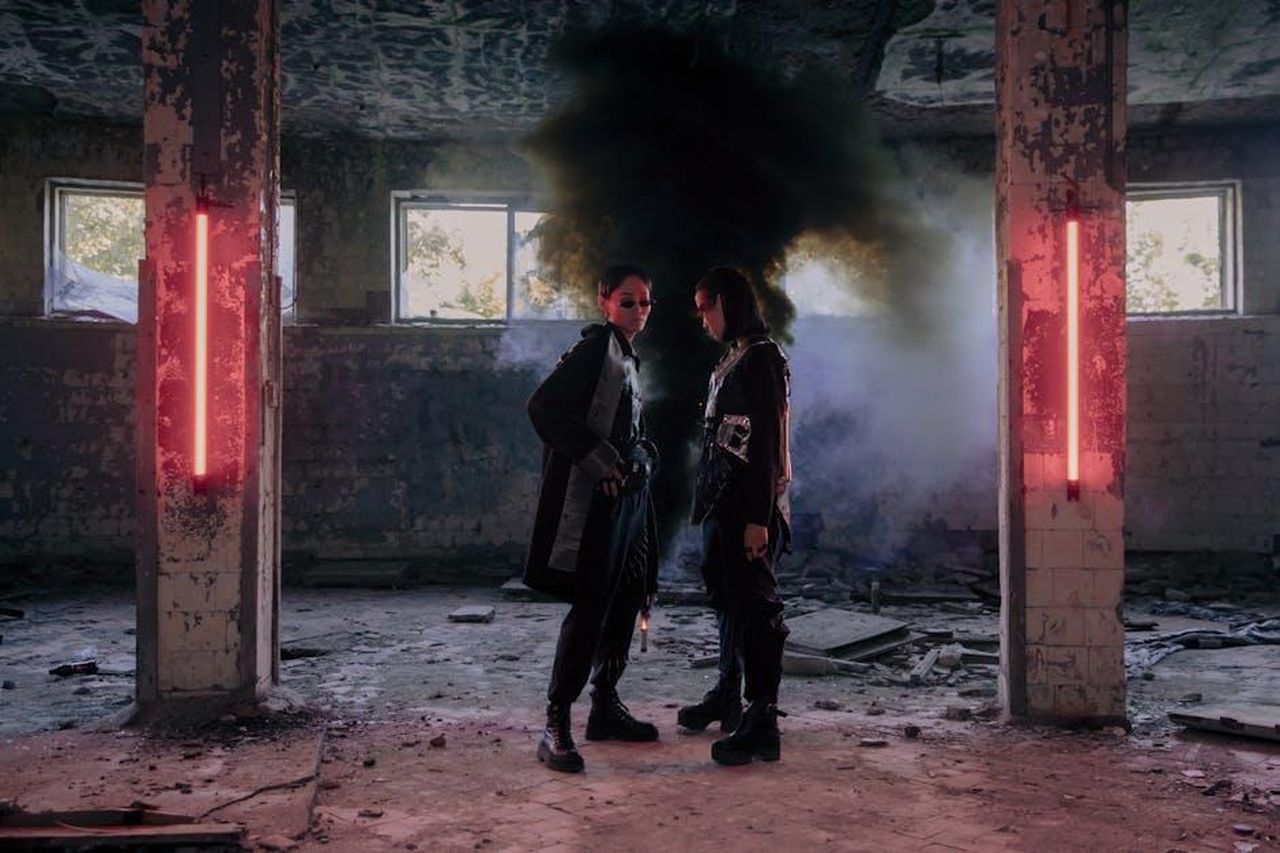 Piani_futuri_per_i_modelli_Mercedes_4X2GYqCbbd - Veicoli24 Source: cottonbro studio - pexels - Two models in a dystopian setting with neon lights and smoke, showcasing futuristic fashion.
