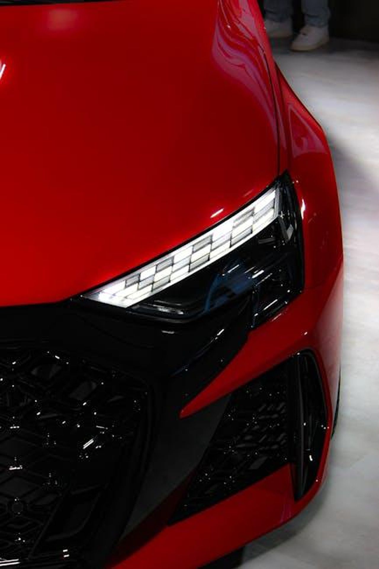 Presentazione_del_Supersport_iQ2POOfS8a - Veicoli24 Source: Aarav Chopra - pexels - Close-up of a modern red sports car with striking headlights on display indoors.