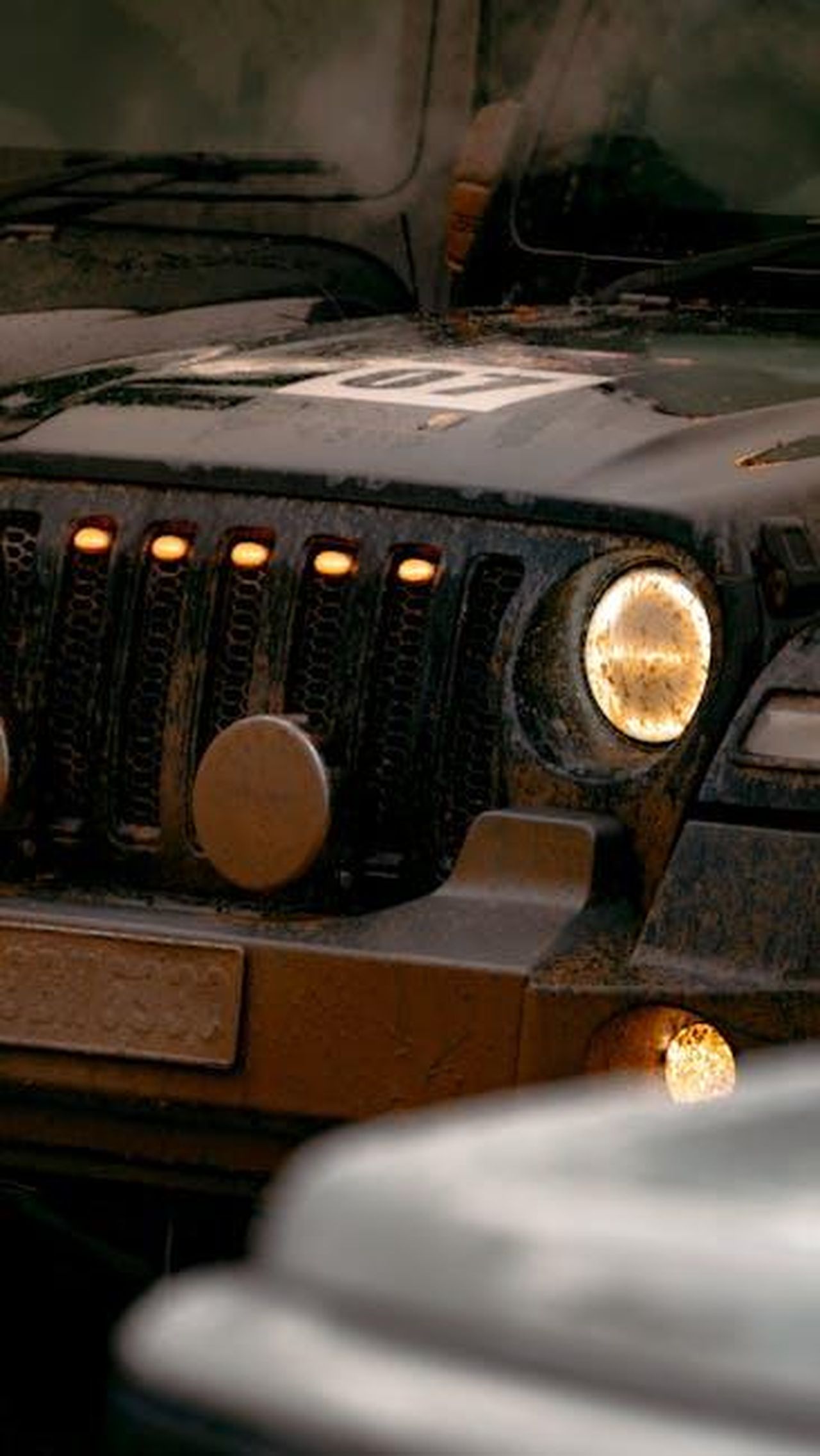 Prestazioni_della_GClass_2024_pm5HhnWgmU - Veicoli24 Source: Sleeba Thomas - pexels - Detailed view of a muddy off-road vehicle with illuminated headlights, showcasing rugged adventure theme.