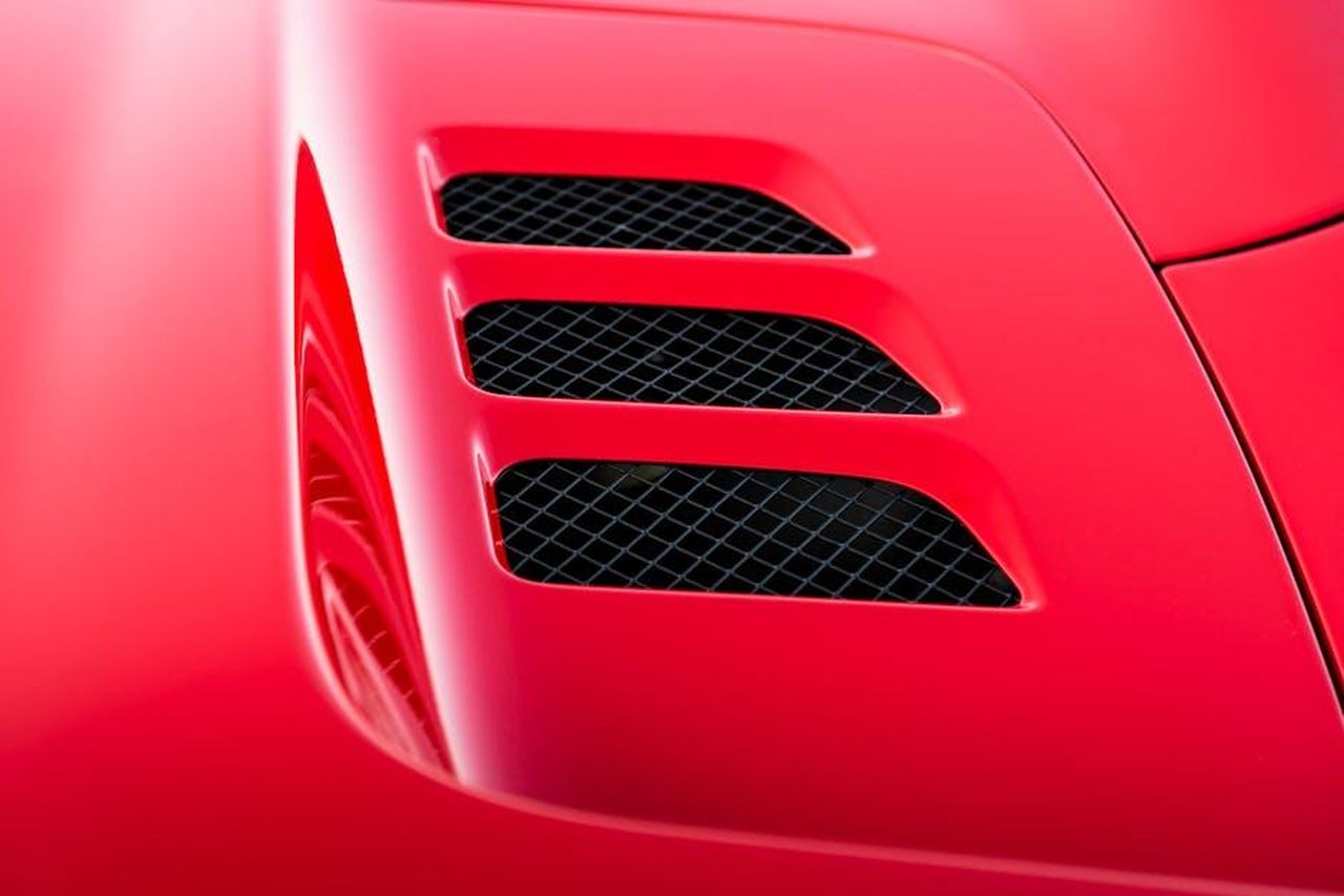 Prestazioni_della_Porsche_911_2025_55jpEV9vQO - Veicoli24 Source: Quentin Martinez - pexels - Detailed close-up of airflow vent on a red luxury sports car hood.