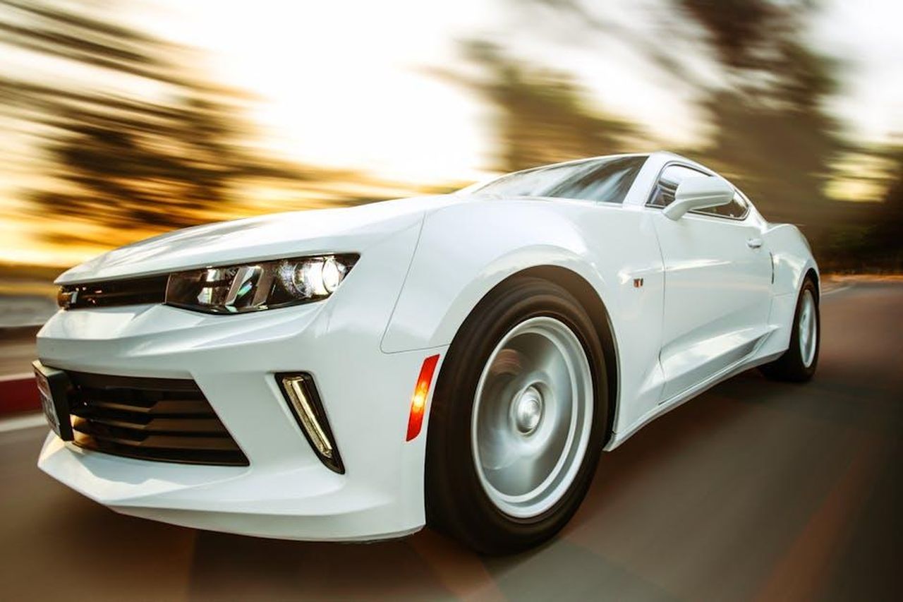 Prestazioni_delle_auto_e_dei_piloti_w6MraTzioJ - Veicoli24 Source: Jesse Zheng - pexels - A white sportscar in motion showcasing speed and style on an open road.