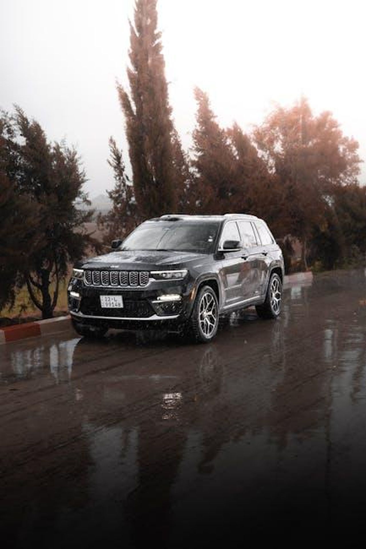 Prestazioni_e_potenza_del_Wrangler_4xe_d6bHrnaobs - Veicoli24 Source: 04iraq - pexels - A modern SUV on a wet road surrounded by autumn trees, creating a stunning travel scene.