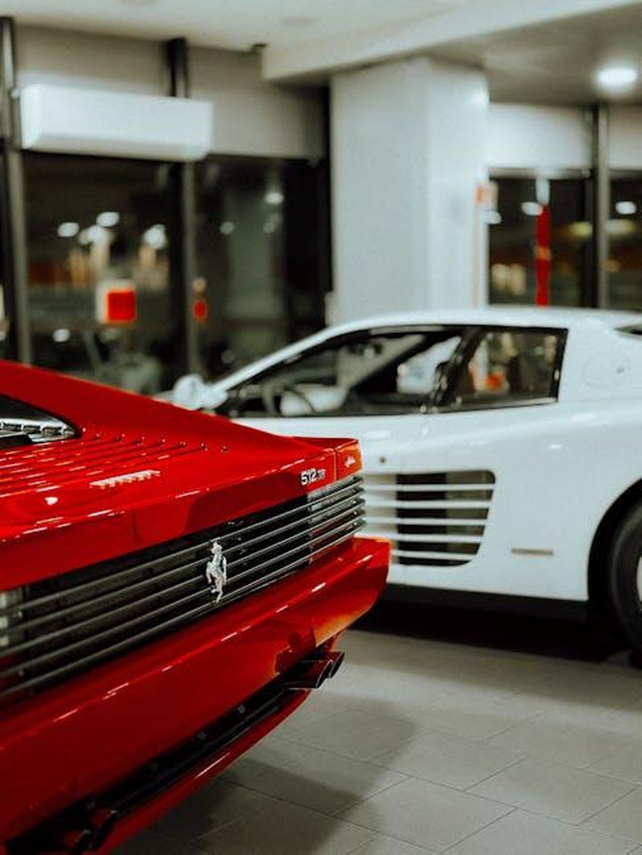 Prestazioni_e_potenza_del_motore_CAPXyK8z6H - Veicoli24 Source: Borta - pexels - Close-up of luxury red and white sports cars in a modern auto showroom.