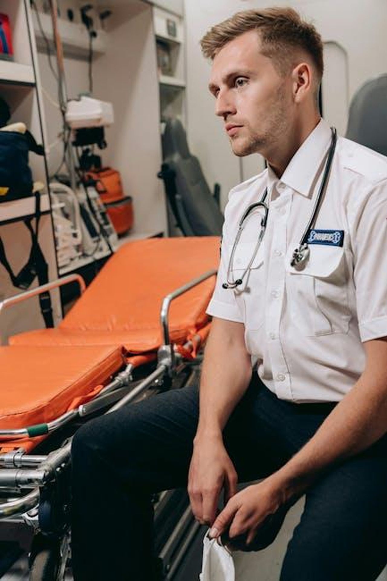 Principi_di_Cura_PreOspedaliera_pvdVb2uPMD - Veicoli24 Source: Mikhail Nilov - pexels - A paramedic in uniform sitting inside an ambulance next to a gurney, ready for an emergency.