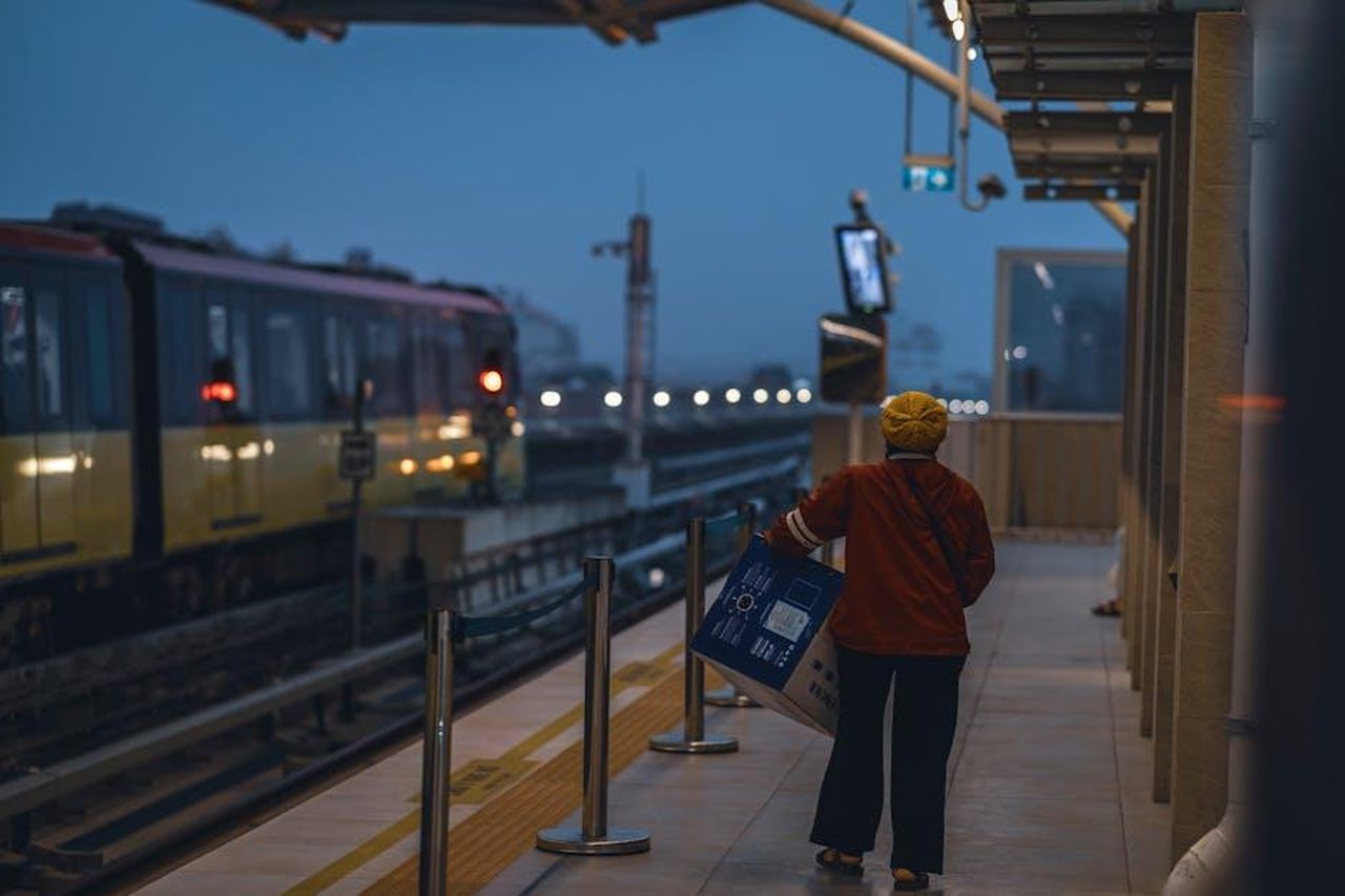 Prossimi_eventi_del_Campionato_FIA_Junior_WRC_2025_BLruvVMaZ0 - Veicoli24 Source: Toàn Văn - pexels - A person at an outdoor train station during twilight, holding a large package.