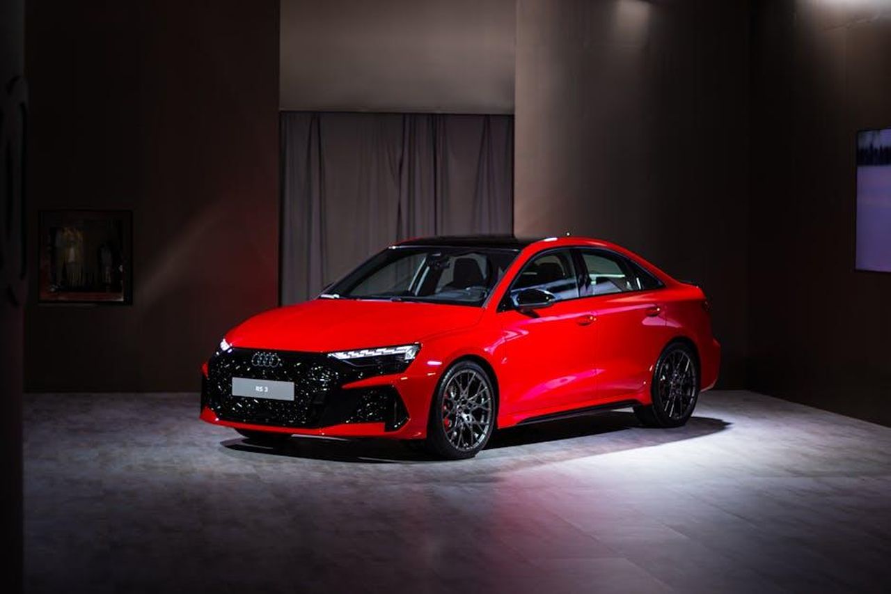 Prossimi_modelli_e_prezzi_ZLPvED1XBc - Veicoli24 Source: Anurag Jamwal - pexels - Red Audi RS on display in a Toronto studio with dramatic lighting.