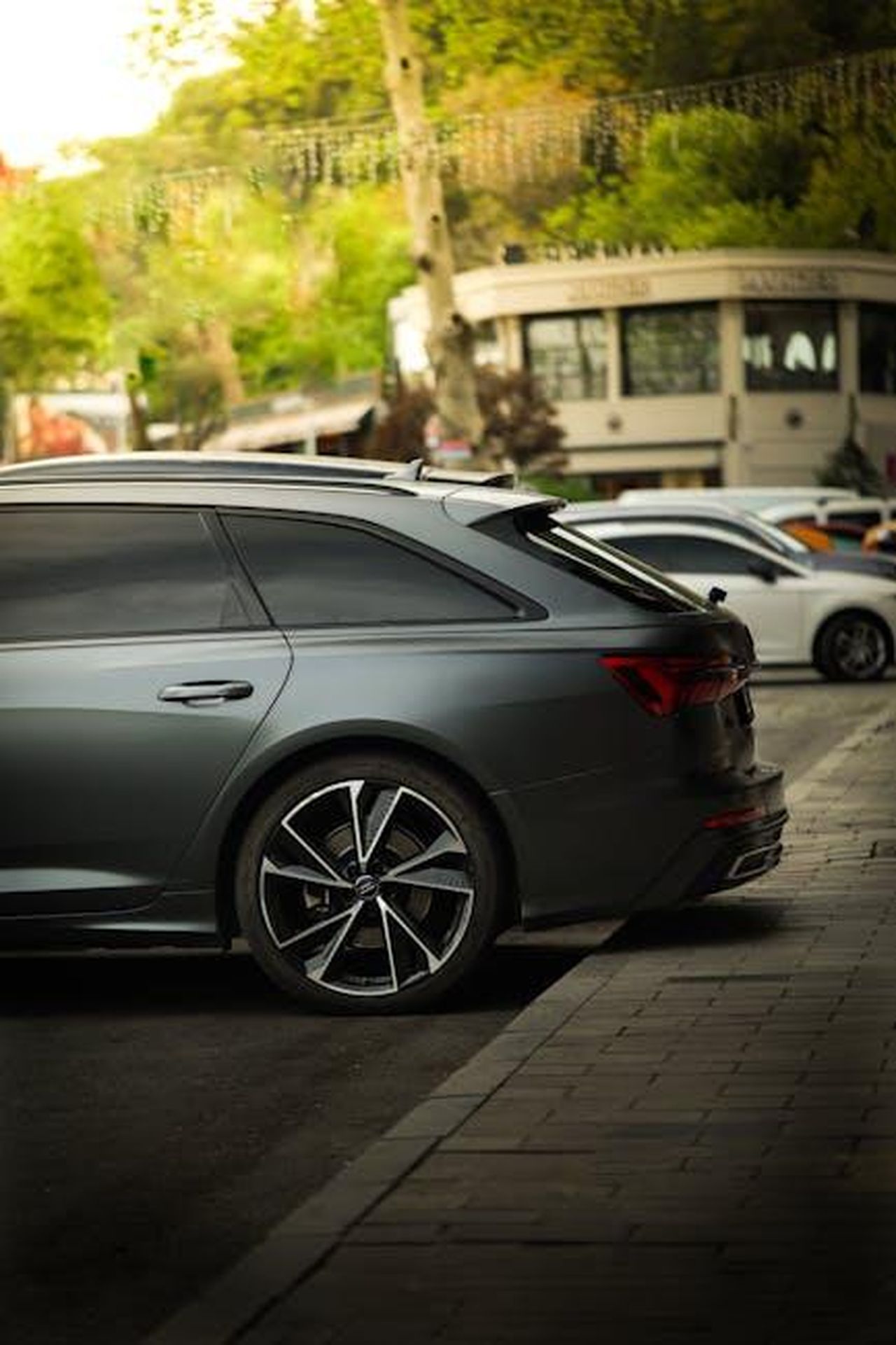 Prototipi_camuffati_del_nuovo_A6_avvistati_in_fase_di_test_7Qlxb2DgNS - Veicoli24 Source: Mustafa Aydemir - pexels - Dynamic shot of a gray Audi A6 parked in bustling İstanbul with lush greenery.