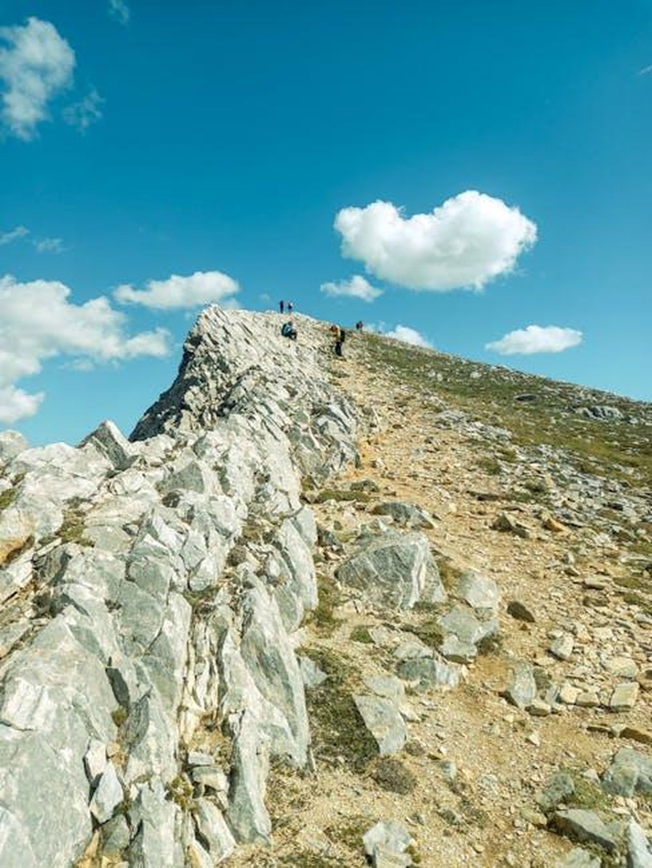 Quanto_costa_la_Subaru_Ascent_2025_bgXloXMVwQ - Veicoli24 Source: Moon - pexels - Scenic mountain ridge with hikers under a bright blue sky with fluffy clouds.