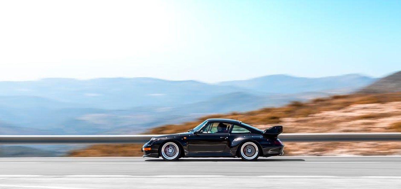 Richiamo_per_i_fari_della_Porsche_911_G31R5VvVaq - Veicoli24 Source: Quentin Martinez - pexels - A sleek black supercar speeding on a curvy mountain road during bright daytime.