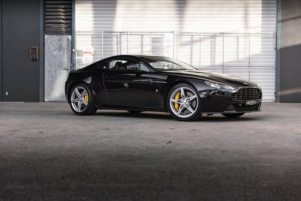 Ritardi_nello_sviluppo_del_Valhalla_DN1jdItlay - Veicoli24 Source: Raimundo Campbell - pexels - Black Aston Martin V8 Vantage parked outdoors in Sydney, showcasing luxury automotive design.
