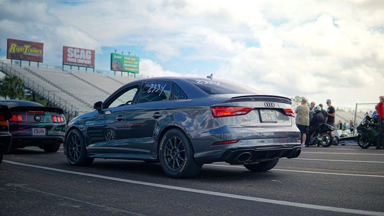Riunione_storica_tra_Sparco_e_Lancia_al_Rally_Racing_Meeting_K1OgwbkBzq - Veicoli24 Source: FBO Media - pexels - Audi S3 sports car at a racetrack gathering with grandstands and people in the background.