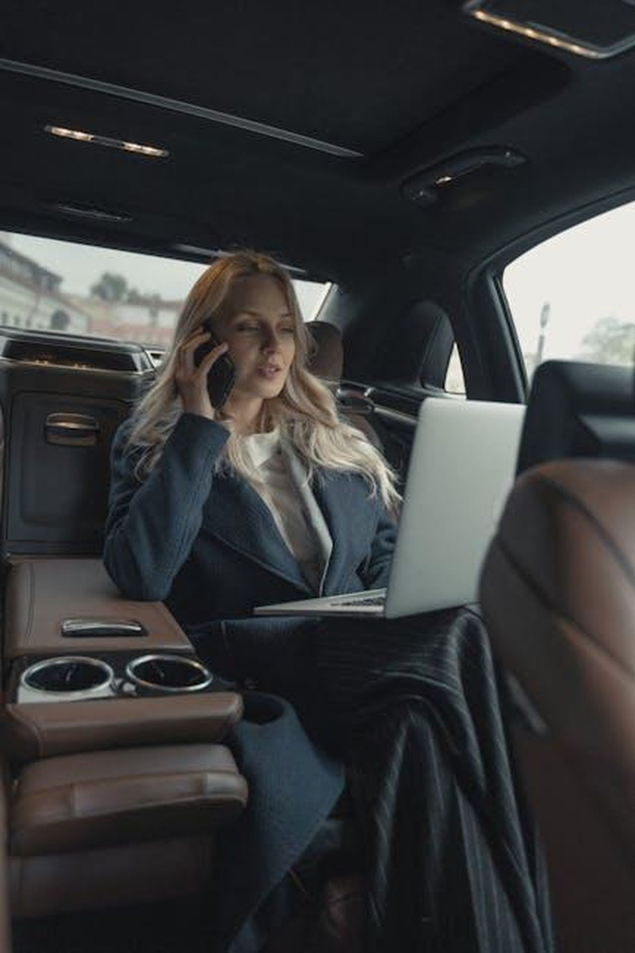Scrutinio_sulle_commissioni_ai_concessionari_83PI6GE43X - Veicoli24 Source: Tima Miroshnichenko - pexels - Confident businesswoman making a call and working on a laptop in a luxury car interior.
