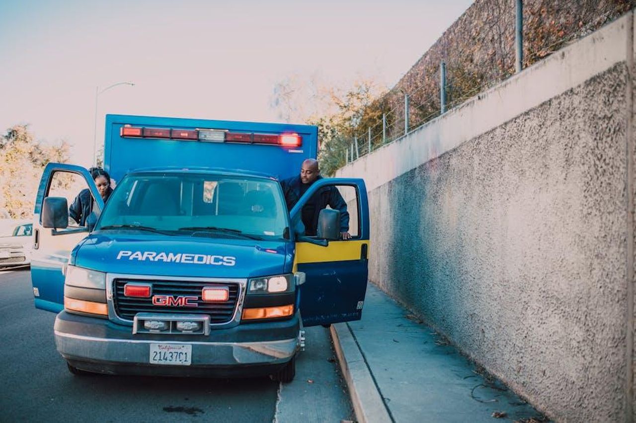Sicurezza_del_GMC_Yukon_2025_frijfWVkW6 - Veicoli24 Source: RDNE Stock project - pexels - Paramedics attending to an emergency roadside with a visible GMC ambulance.