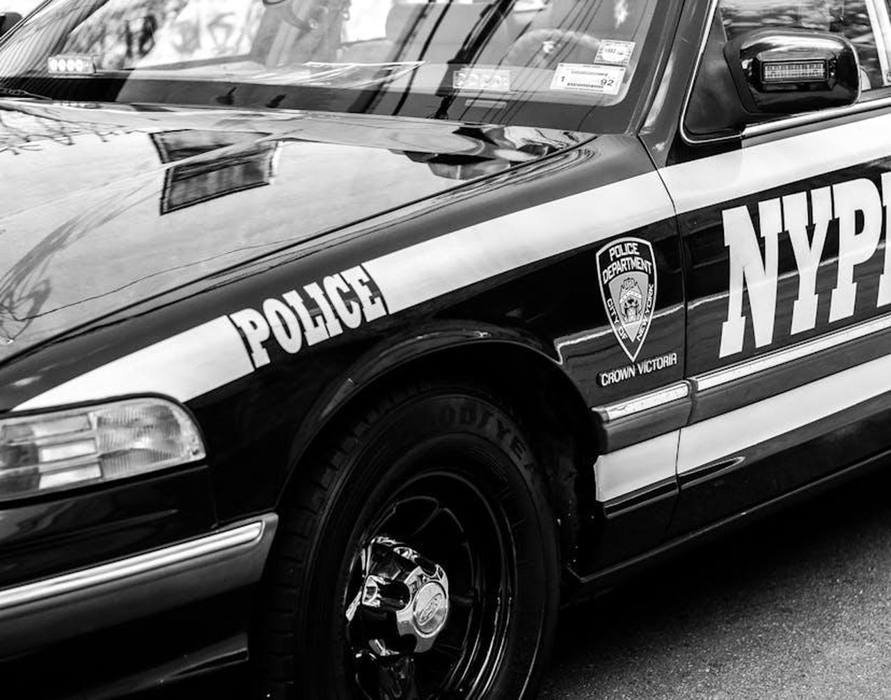 Sicurezza_della_Cadillac_CT5_2025_gLNz7Vl2OC - Veicoli24 Source: Marjorie Matias - pexels - Classic NYPD police car captured on the street in black and white, highlighting urban law enforcement.
