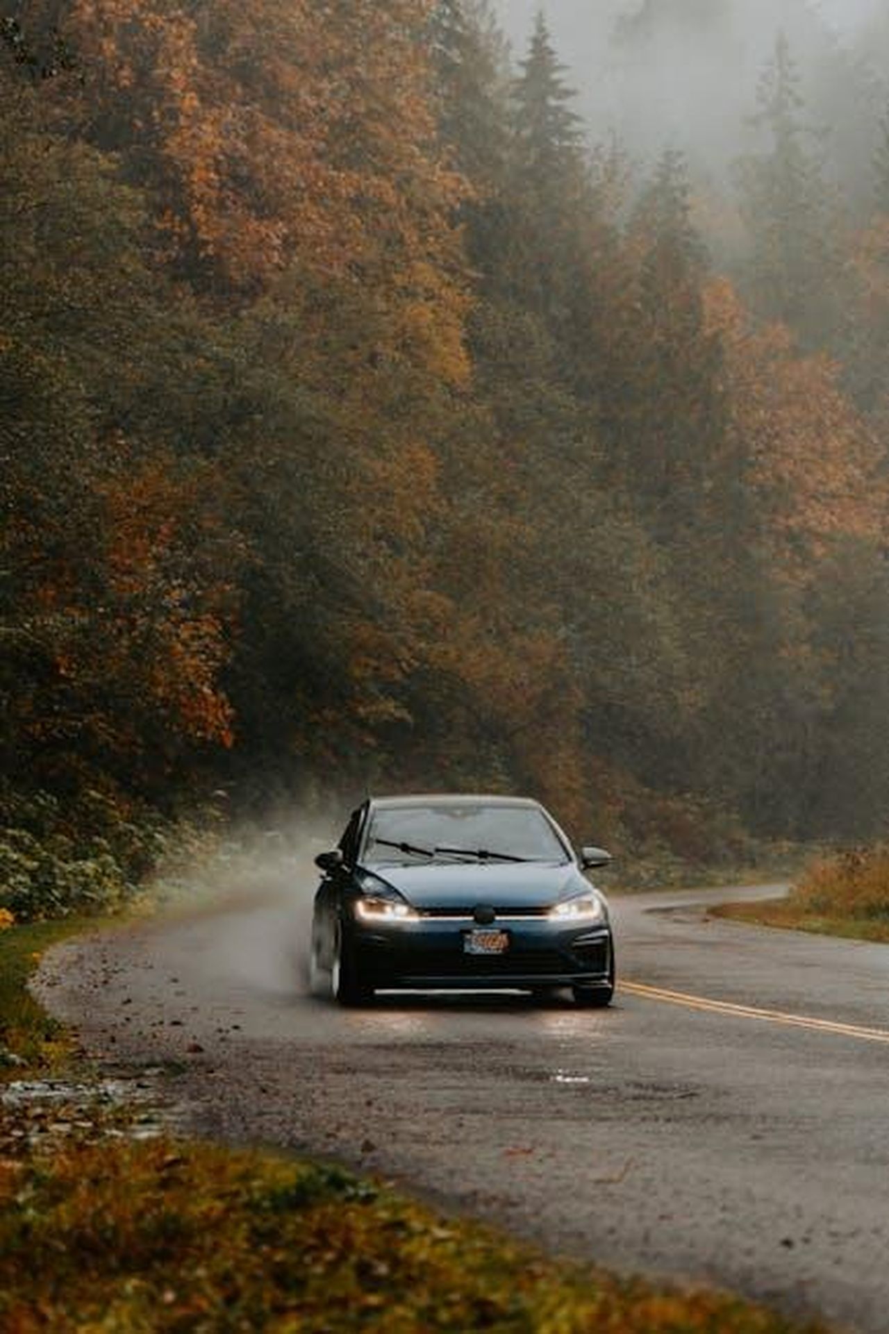 Sicurezza_della_Mitsubishi_Outlander_2025_GP1muaUaaQ - Veicoli24 Source: Luke Miller - pexels - A car navigates a winding road through a foggy, autumn forest, surrounded by colorful trees.