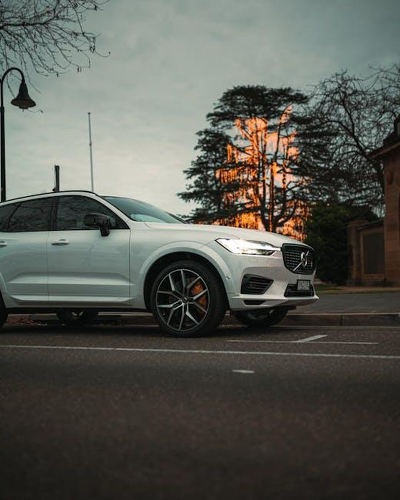Sicurezza_della_Polestar_2_9MV1uAnH6T - Veicoli24 Source: Matt Jerome Connor - pexels - A sleek white SUV parked on an urban street during dusk, showcasing elegance and modern design.