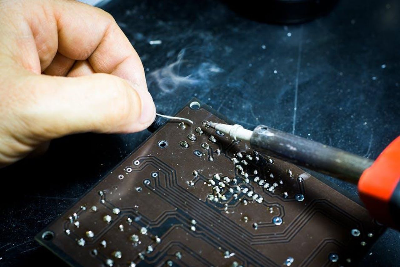 Stabilimento_BMW_di_Landshut_un_produttore_di_componenti_multitalento_vbSXMaPNTm - Veicoli24 Source: Blaz Erzetic - pexels - Hand soldering on a printed circuit board, showcasing electronic craftsmanship.