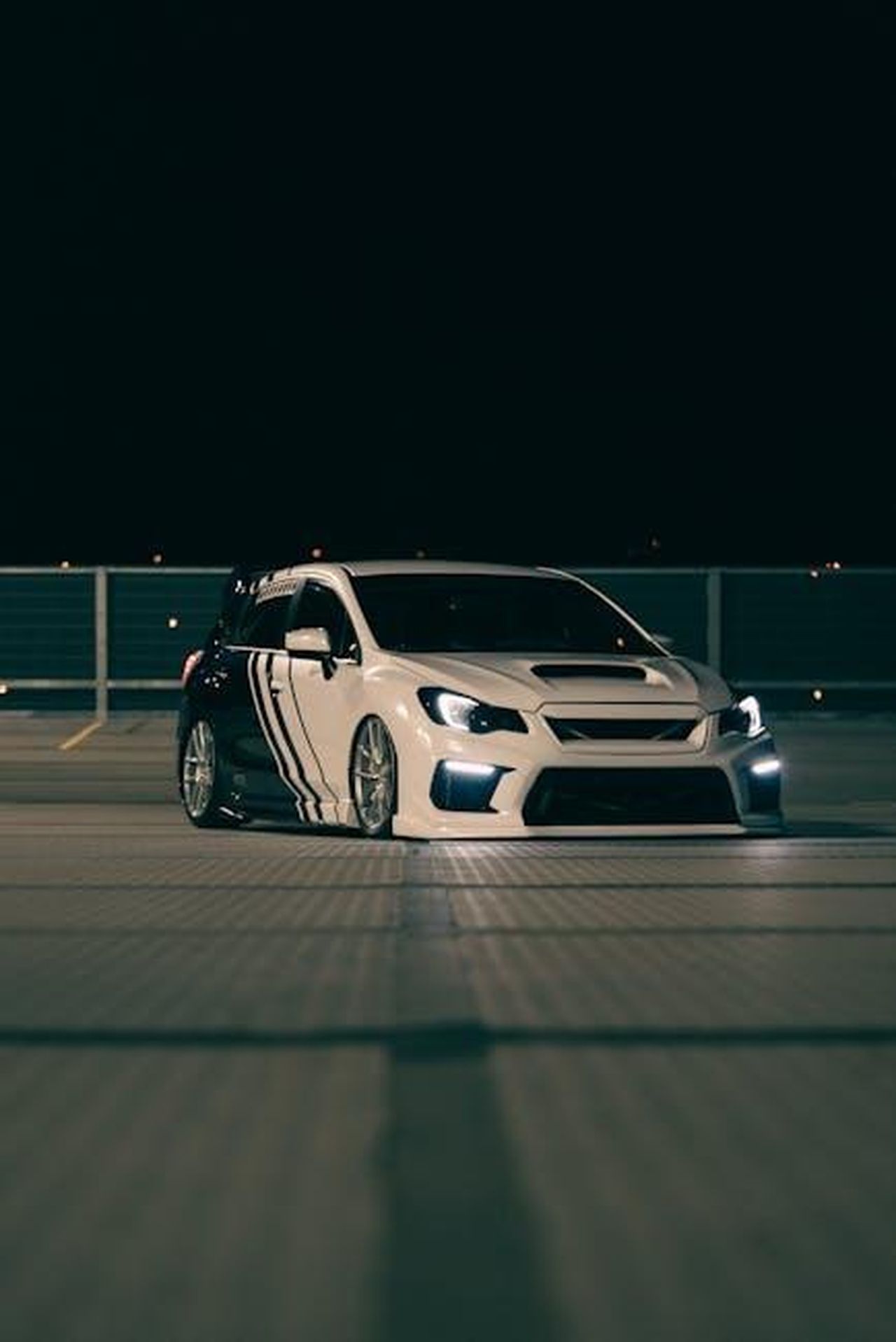 Stile_della_Subaru_Ascent_2025_8ht4Hpxtmn - Veicoli24 Source: Erik Mclean - pexels - A vibrant night scene capturing a customized Subaru WRX sports car in a parking lot.