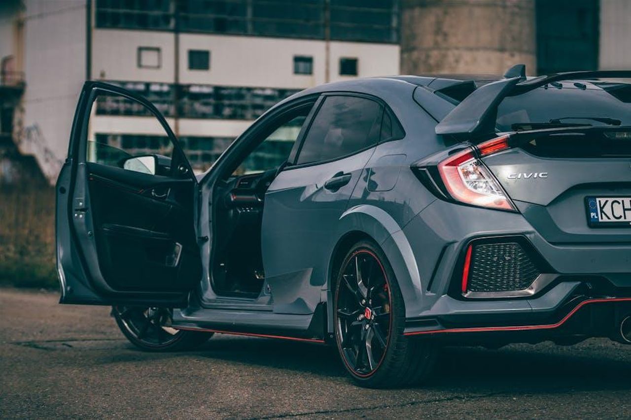 Stili_di_carrozzeria_della_Honda_Civic_Hybrid_h12eNqECU2 - Veicoli24 Source: Jakub Pabis - pexels - A stylish grey Honda Civic Type R with door ajar, showcasing its sporty features in an urban environment.