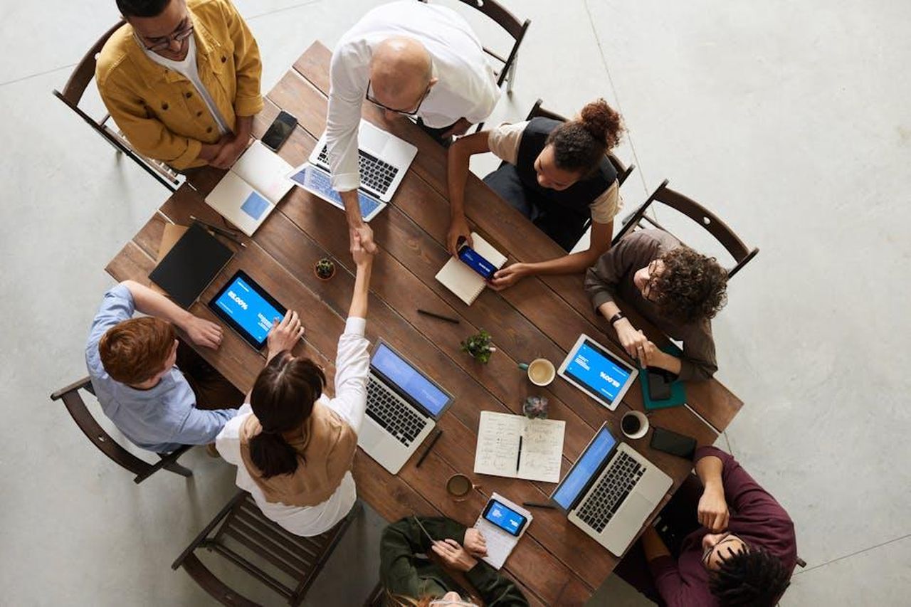 Strategia_di_crescita_e_sinergie_aziendali_ce5LutfrWC - Veicoli24 Source: fauxels - pexels - Top view of a diverse team collaborating in an office setting with laptops and tablets, promoting cooperation.