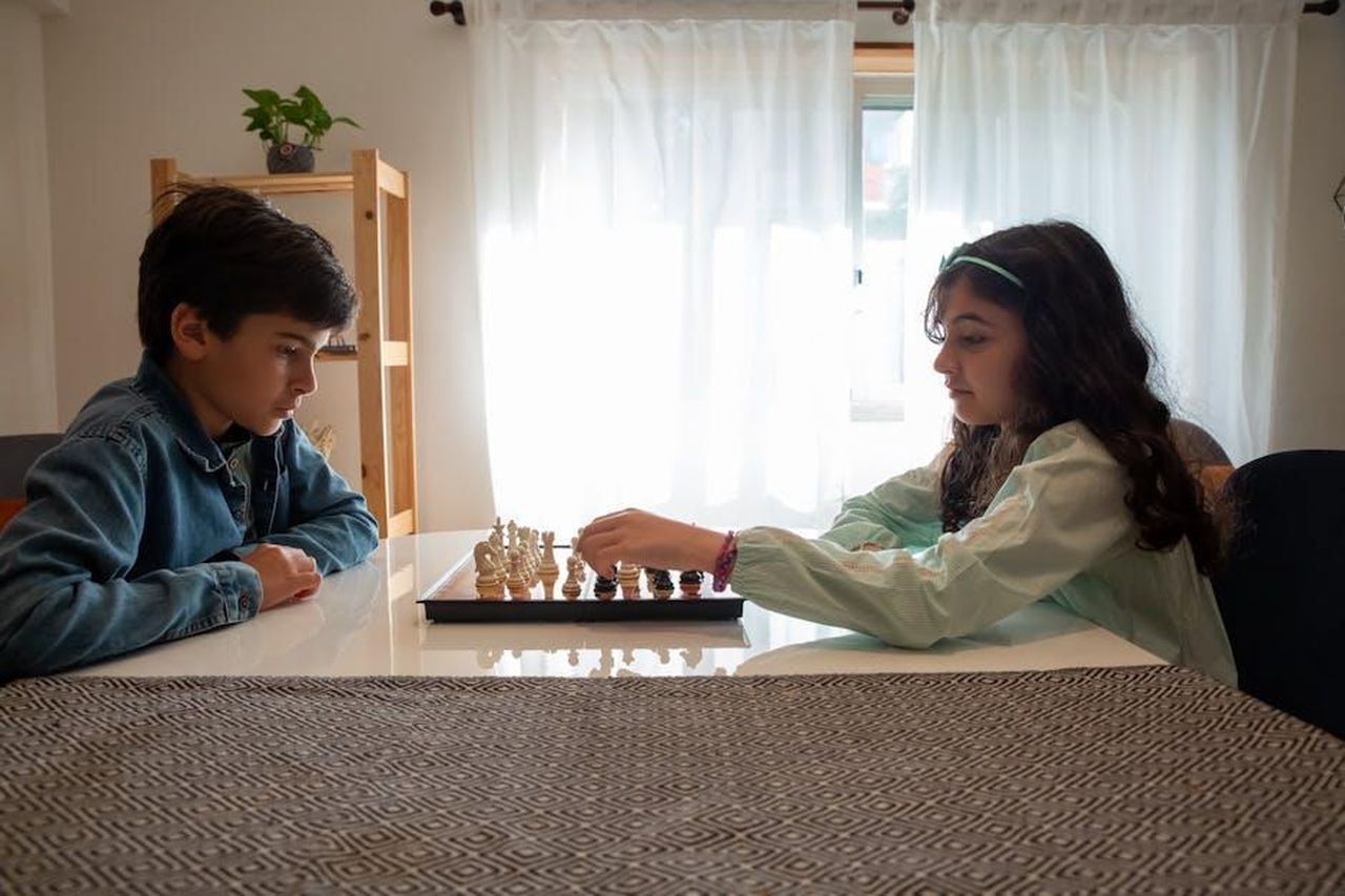 Strategia_di_elettrificazione_di_Kia_7pFI6sEyJK - Veicoli24 Source: Kampus Production - pexels - Two children engaged in a chess game indoors, captured in Portugal.