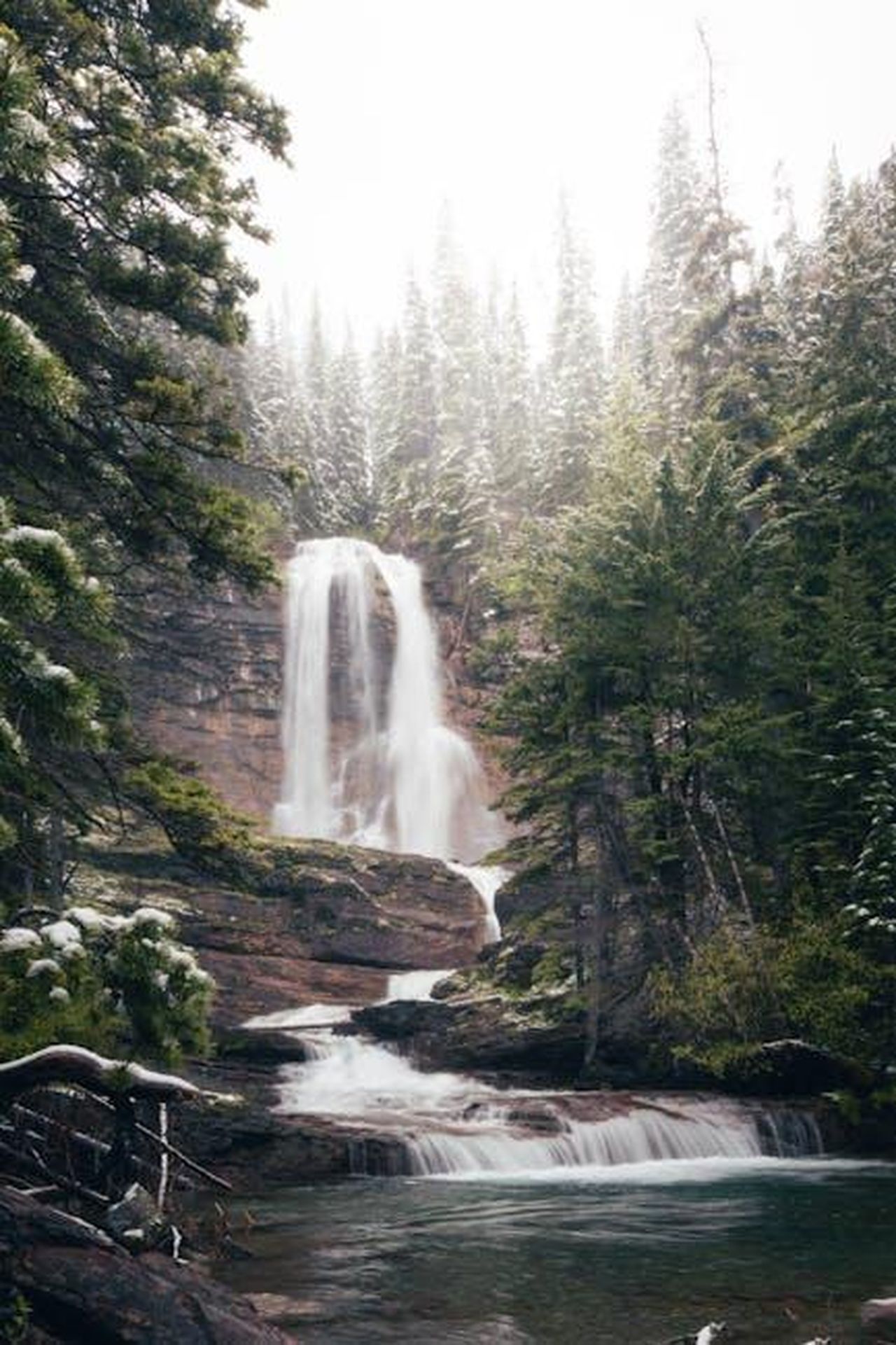 Strategia_di_lancio_di_Alpine_negli_Stati_Uniti_ld4puSyuyq - Veicoli24 Source: Branden Stephenson - pexels - Serene winter waterfall surrounded by snow-laden trees in Glacier National Park, Montana.