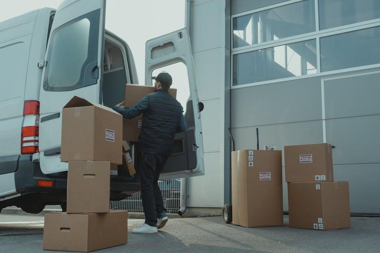 Tabella_delle_auto_pi_affidabili_YtGrg5w8lA - Veicoli24 Source: Tima Miroshnichenko - pexels - A delivery man unloading cardboard boxes from a van at a warehouse during the day.