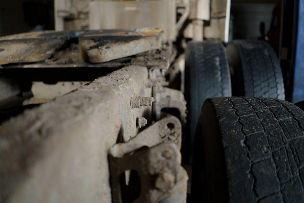 Tecnologia_del_telaio_e_sistemi_di_controllo_specifici_per_il_modello_dwObzP7szk - Veicoli24 Source: cottonbro studio - pexels - Detailed close-up of a dirty truck chassis and tires, showcasing automotive machinery.