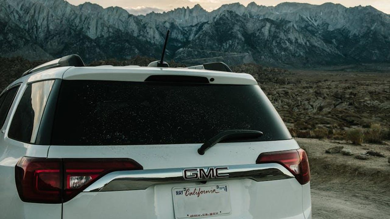 Tecnologia_e_comfort_del_GMC_Yukon_2025_x9Js0n7hfh - Veicoli24 Source: Athena Sandrini - pexels - White SUV parked in rugged terrain with majestic mountain view.